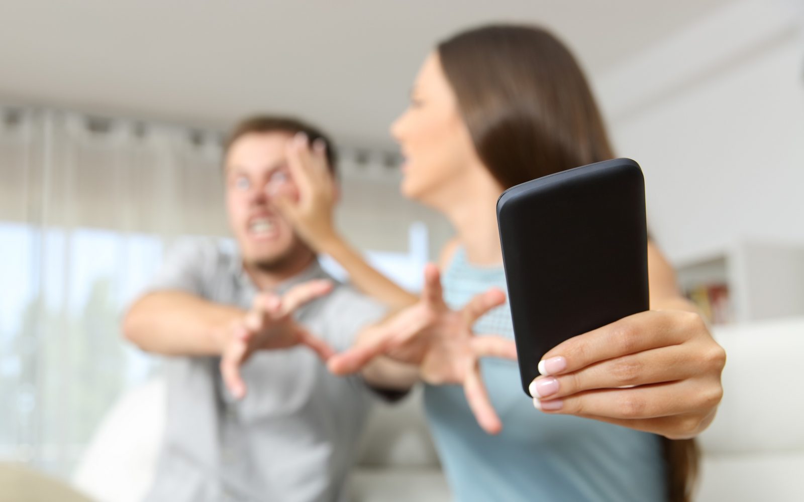 Jezen par, moški in ženska, se prepirata in se borita za mobilni telefon.