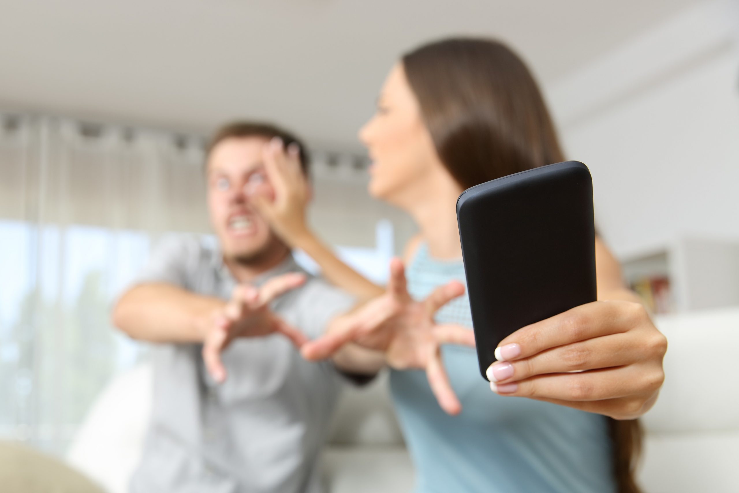 Jezen par, moški in ženska, se prepirata in se borita za mobilni telefon.