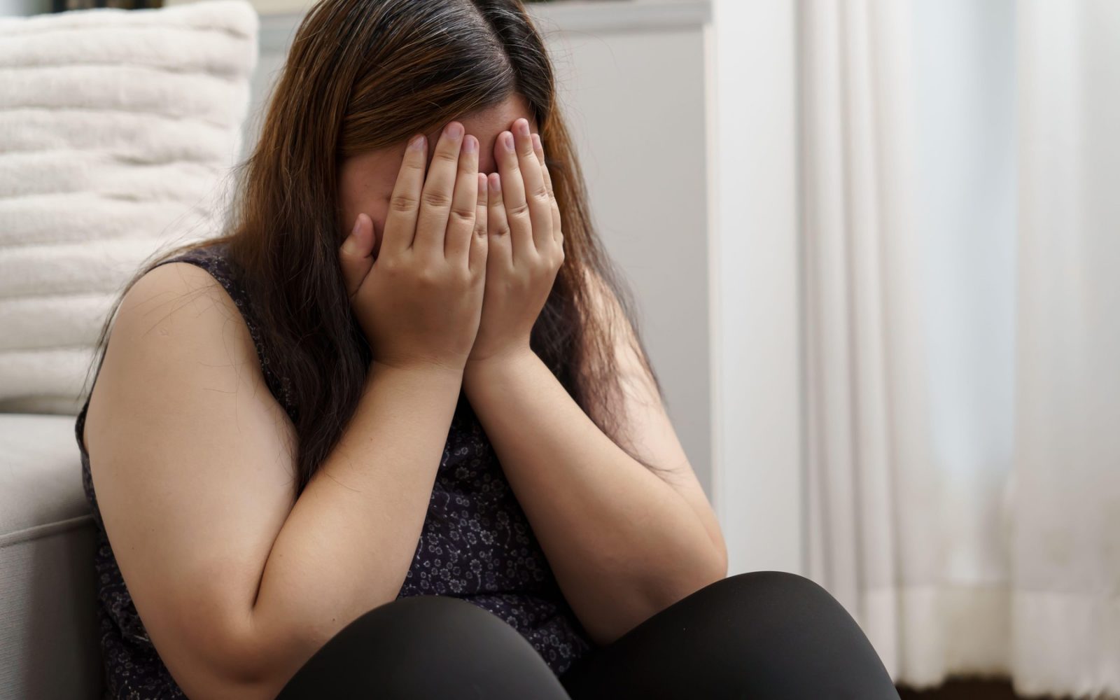 Ženska, ki se drži za glavo zaradi utrujenosti in stresa – simptomi povišanega kortizola