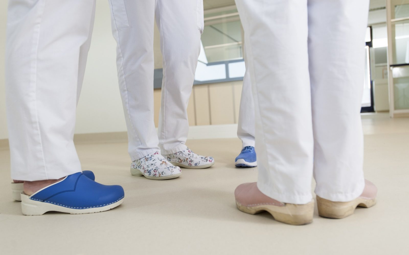 Spodnji del skupine medicinskih sester in zdravnikov, ki nosijo kirurške cokle