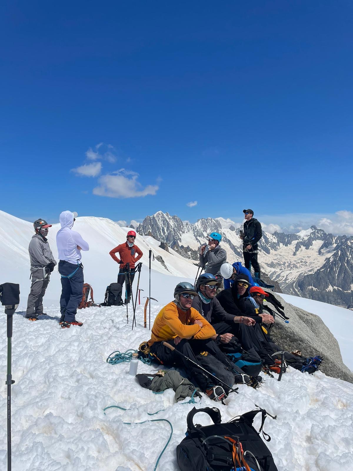 Skupina nasmejanih udeležencev odprave na Mont Blanc s hemofilijo, z mogočnimi Alpami v ozadju.