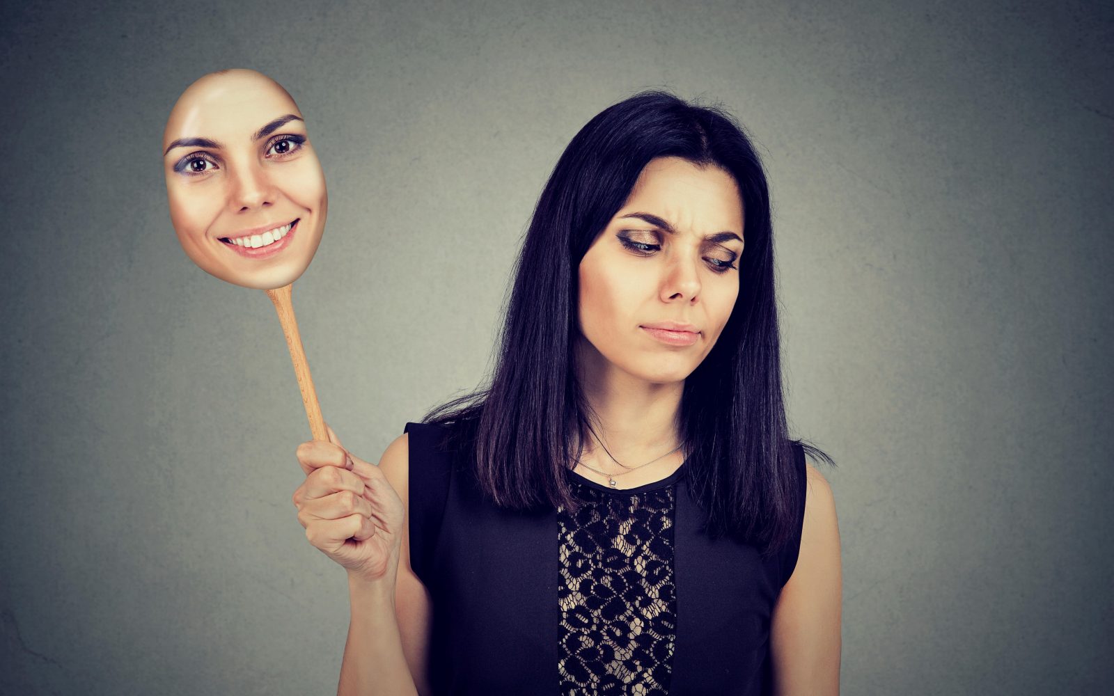 Žalostna ženska v rokah drži masko z nasmejanim obrazom