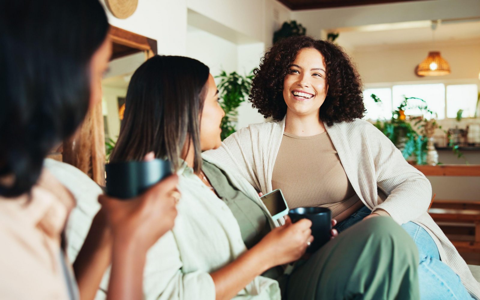 Skupina prijateljic, ki sedijo na kavču in se odprto pogovarjajo o svojih problemih ter si nudijo podporo pri soočanju z duševnimi stiskami.