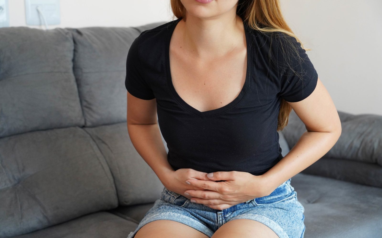 Ženska z bolečinami v spodnjem delu trebuha – eden izmed možnih simptomov raka jajčnikov.