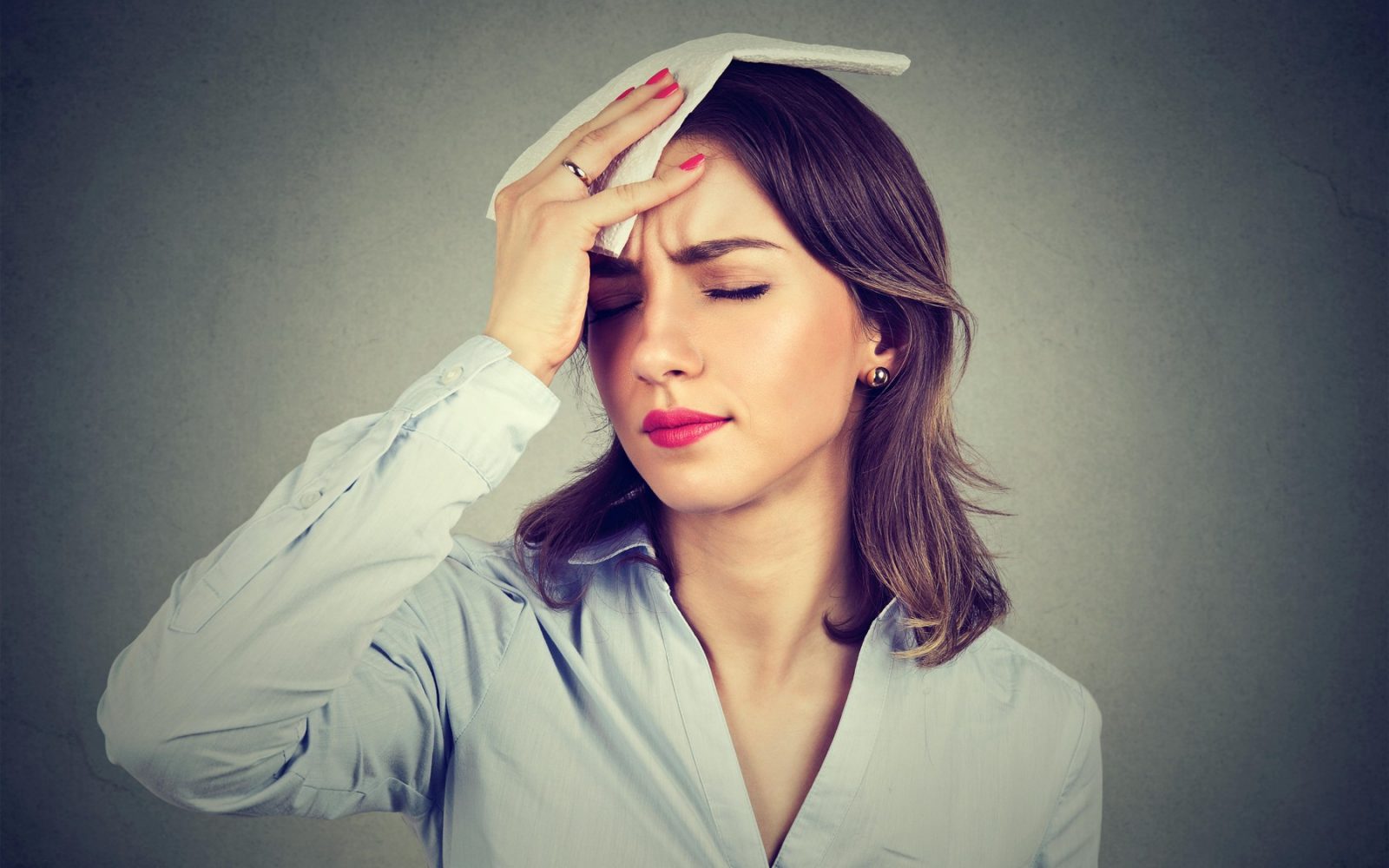 Ženska s simptomi pregretja si hladi čelo – prikaz težav zaradi vročine in pomena termoregulacije ter zaščitnih ukrepov v vročih dneh.