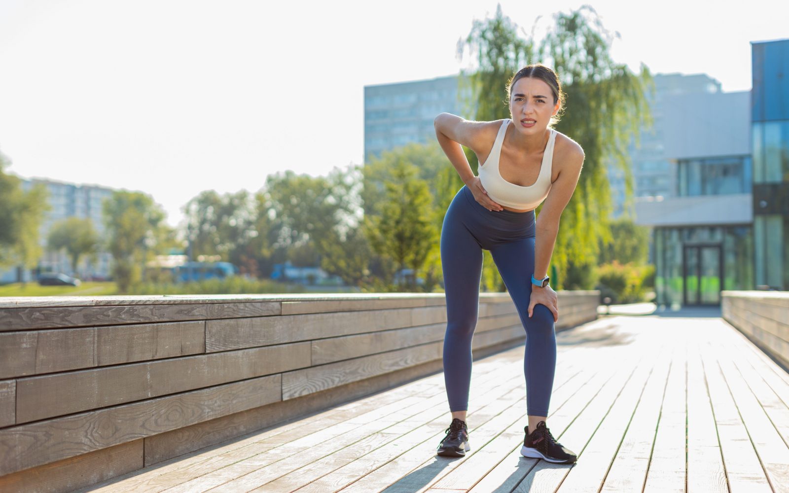 Ženska športnica se drži za trebuh, špikanje med tekom, bodec, bolečine v trebuhu med vadbo