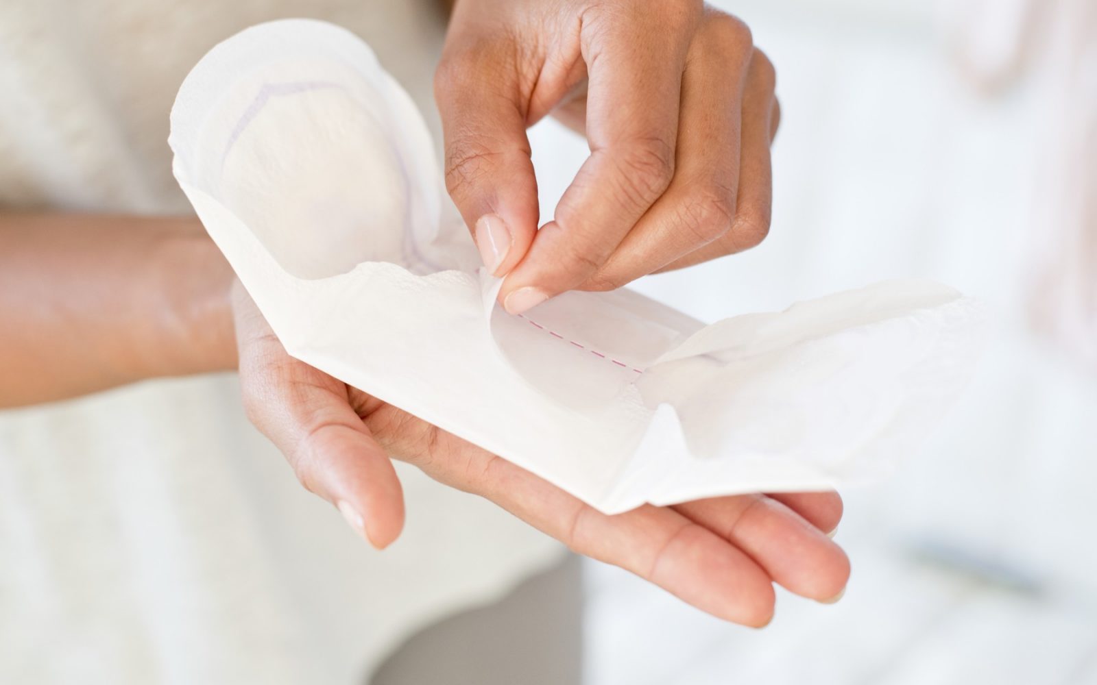 enska roka, ki odpira higienski vložek – ilustracija za uporabo MenstruAI, inovativnega testa za zgodnje odkrivanje raka in vnetij v menstrualni krvi