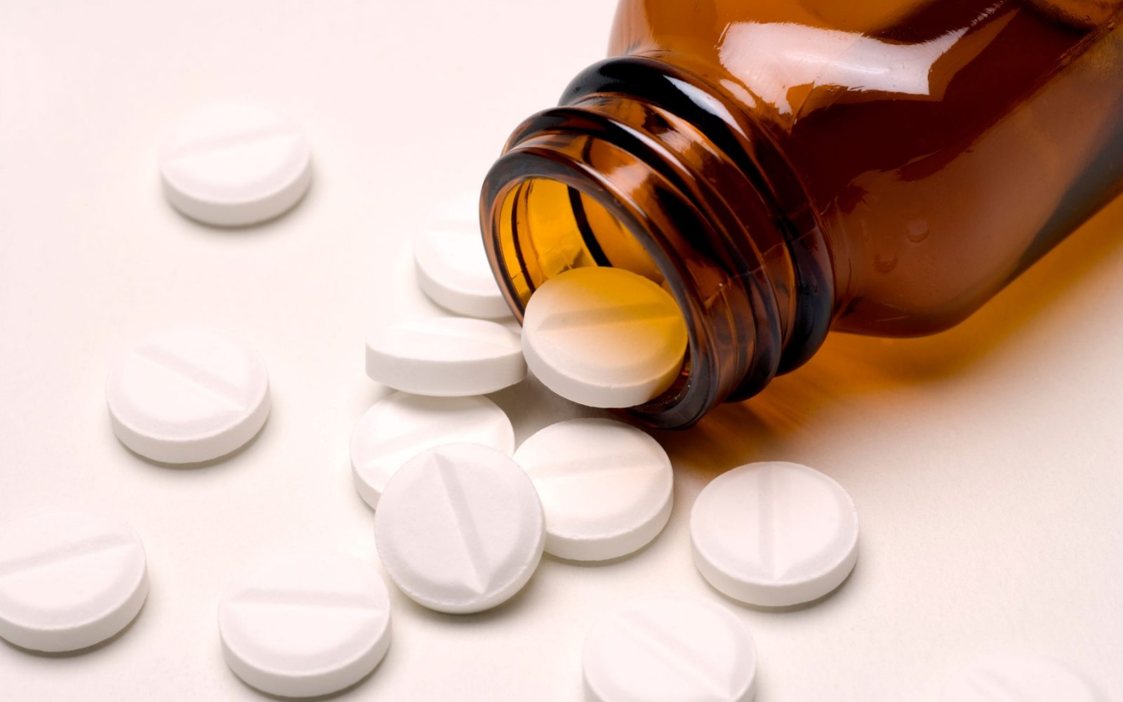 Tablete, zdravila ali tableti, ki se razsipajo iz rjave steklene stekleničke za zdravila – aspirin ali paracetamol.