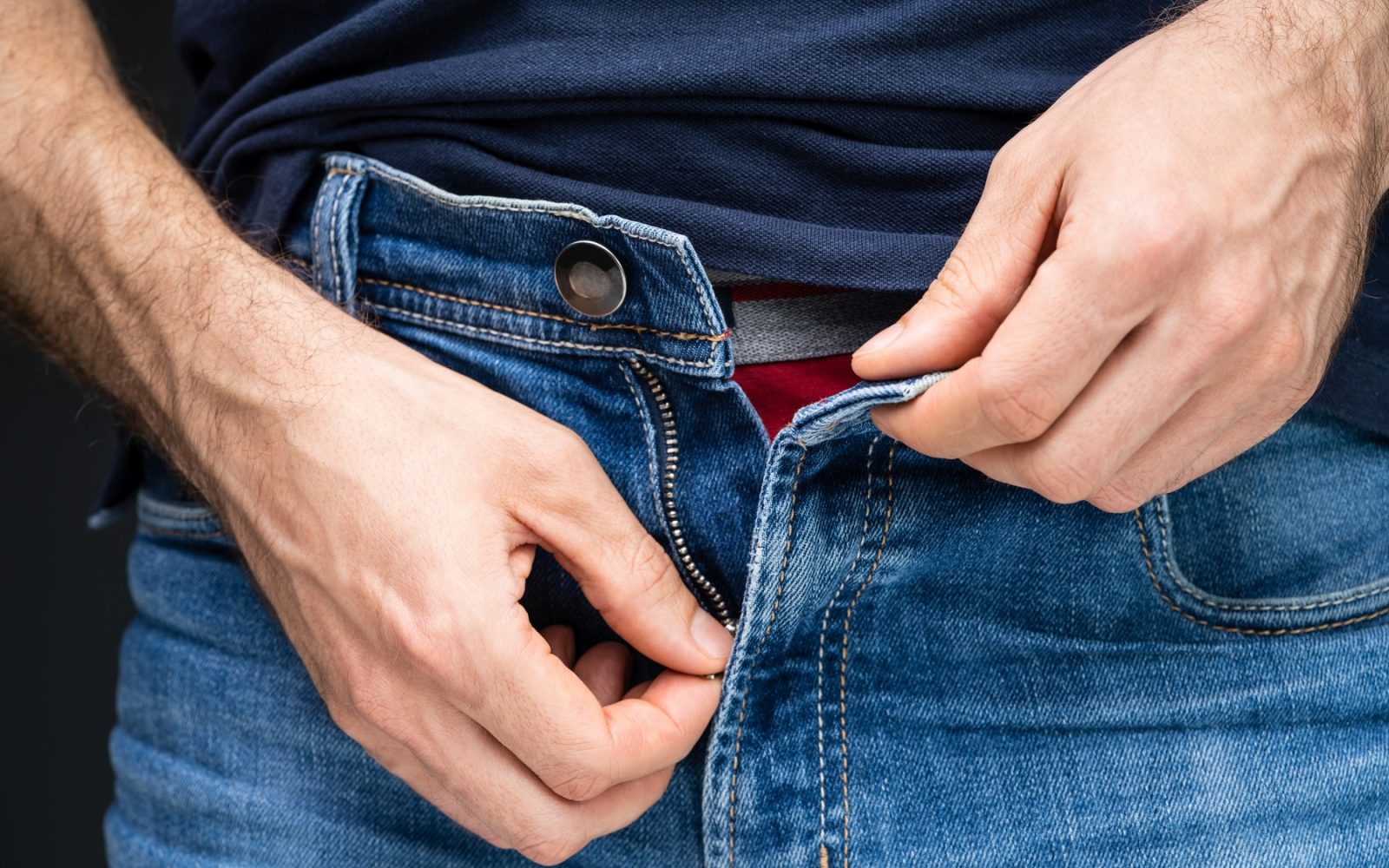 Moški si zapenja zadrgo na kavbojkah – simbolno prikazano spolno zdravje poleti