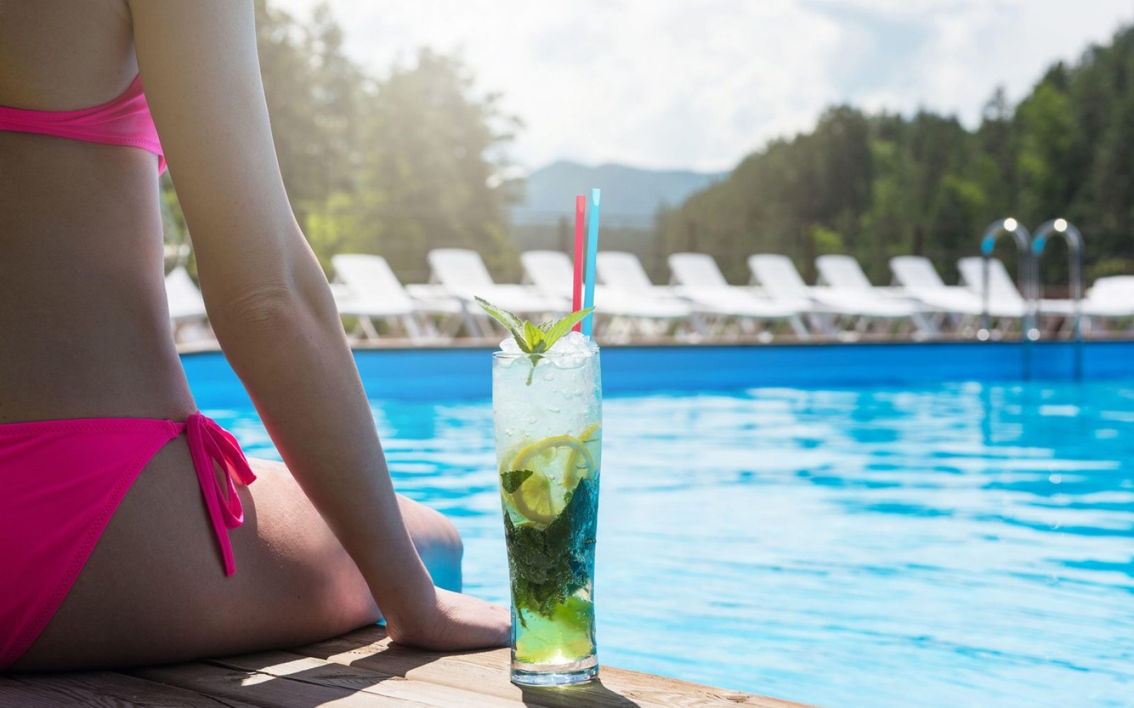 Žesnka pije mojito ob bazenu. Limeta lahko povzroči alergijsko reakcijo.