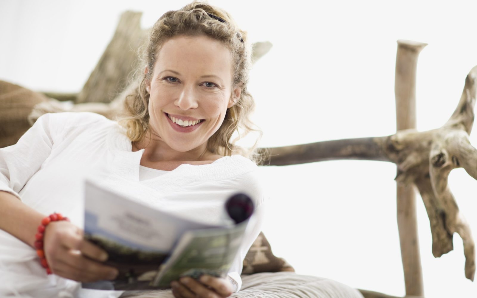 Nasmejana ženska srednjih let bere članek o vplivu vitamina D na staranje