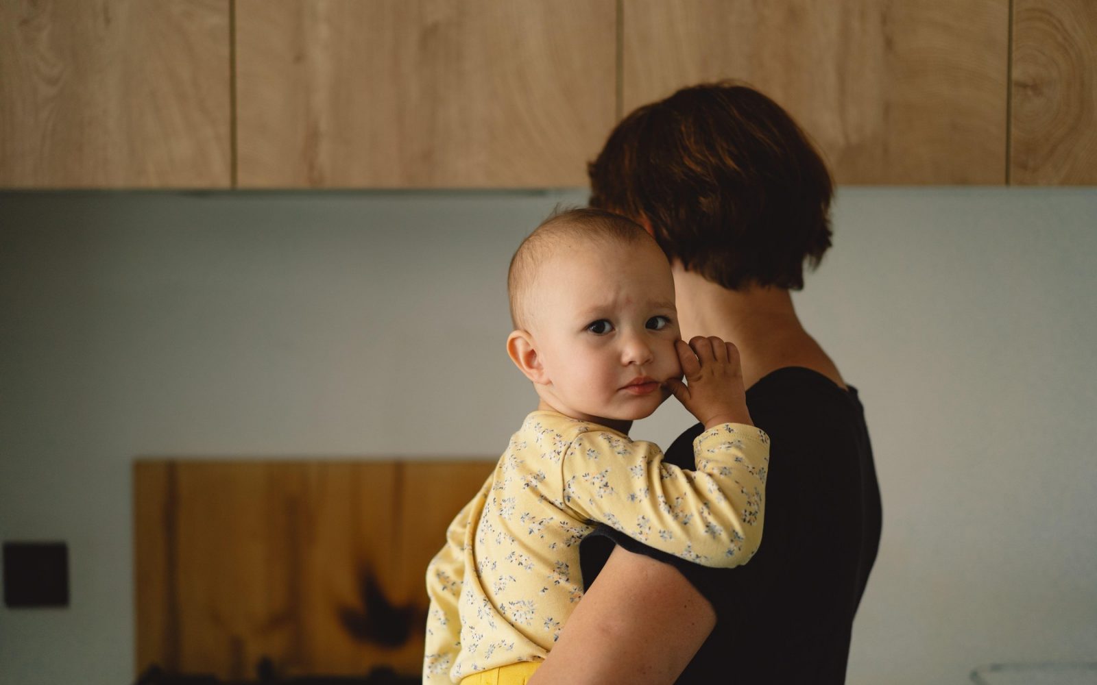Mati stoji v kuhinji, v naročju zima dojenčka, ki je pred tem jokal