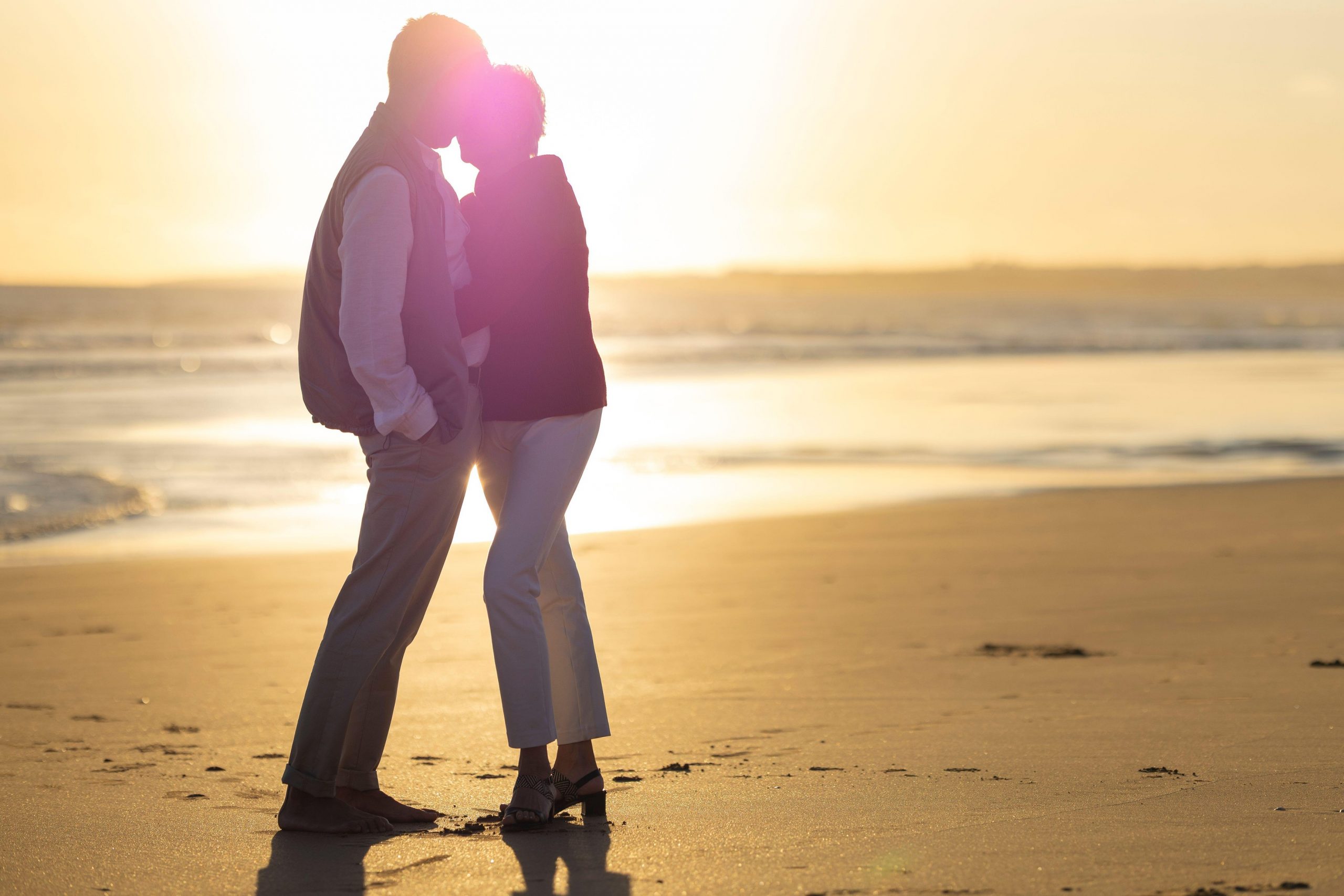 Zdrav starejši par uživa na plaži ob sončnem zahodu