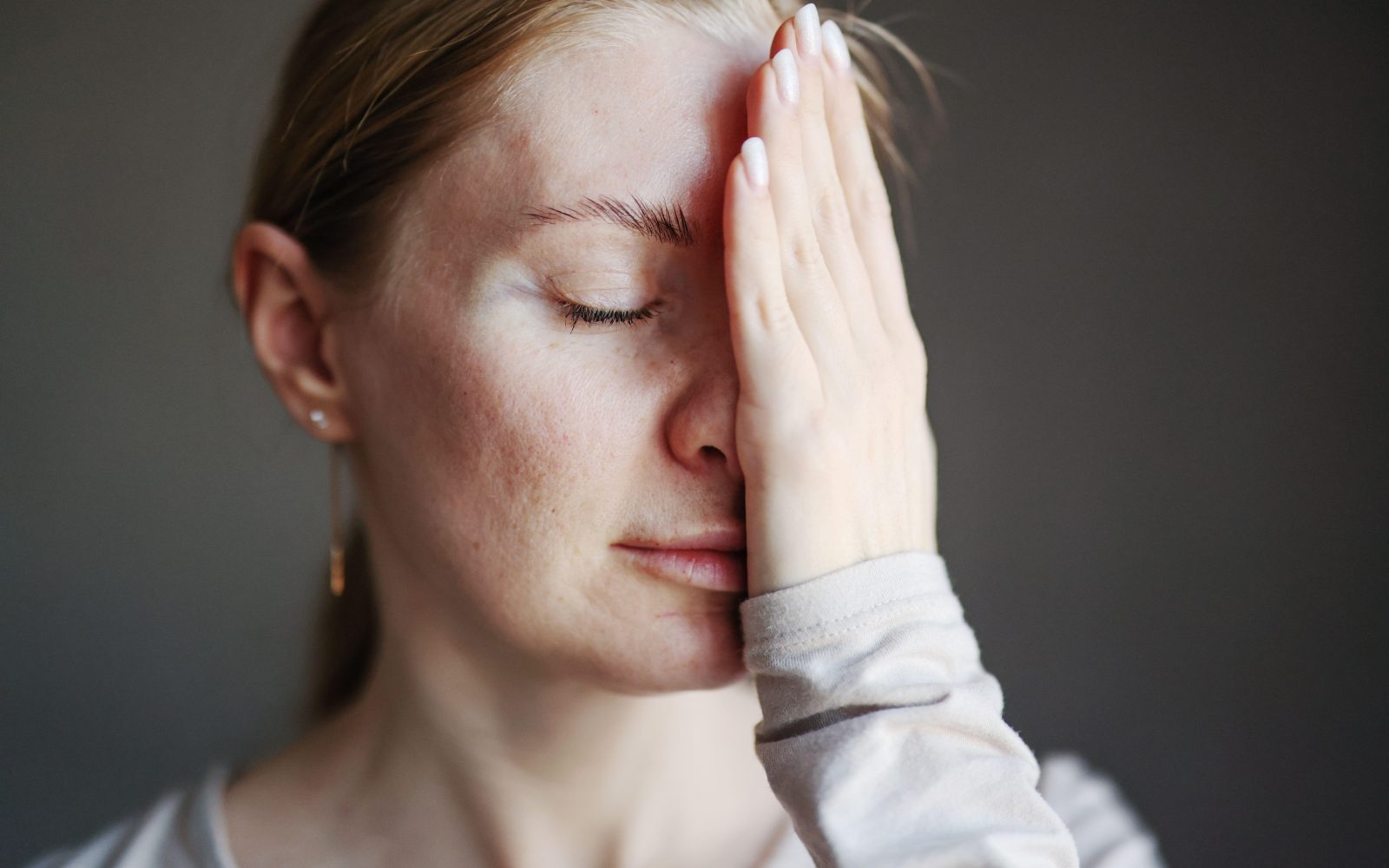 Ženska se drži za obraz; simbolika nege problematične kože