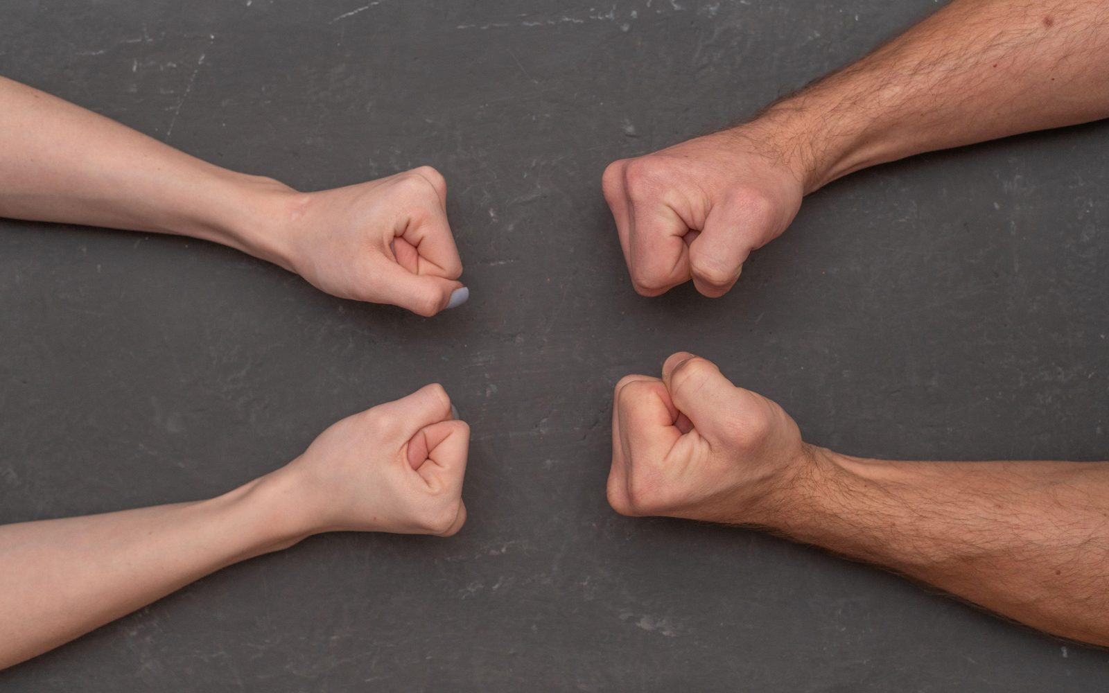 V pest stisnjene dlani ženske in moškega. Koncept neenakosti, zlasti med spoloma.