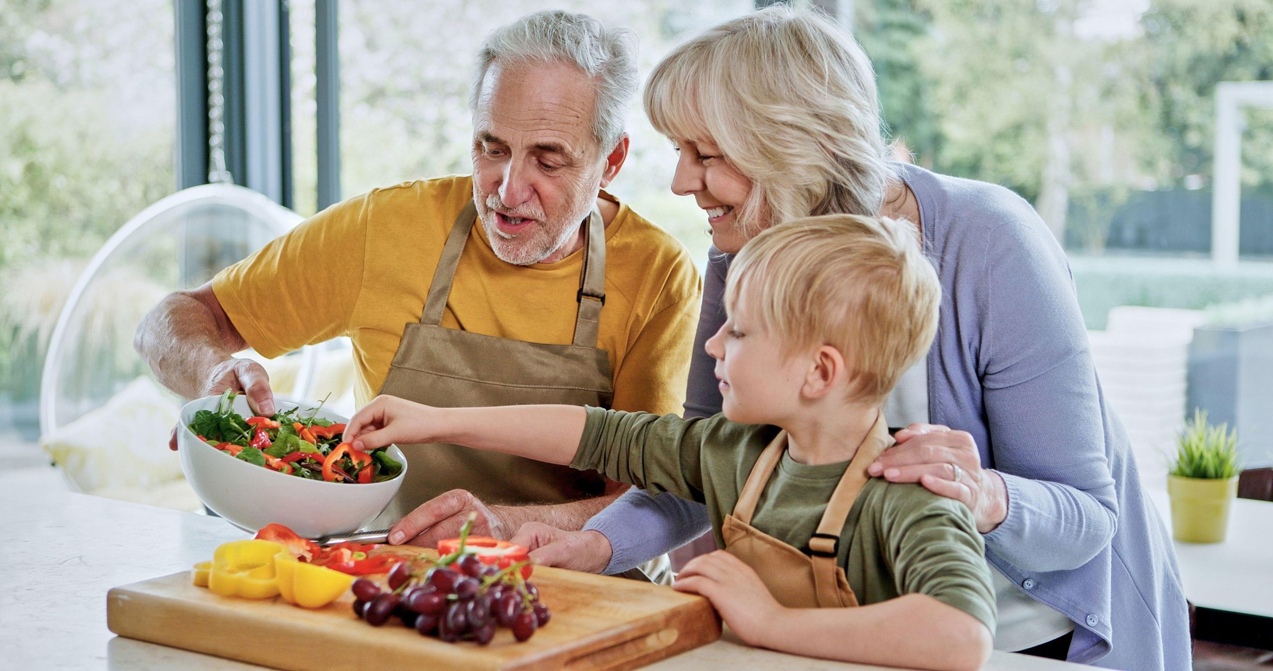 Otrok s pomočjo babice in dedka pripravlja svežo poletno solato iz lokalnih, ekološko pridelanih sestavin.