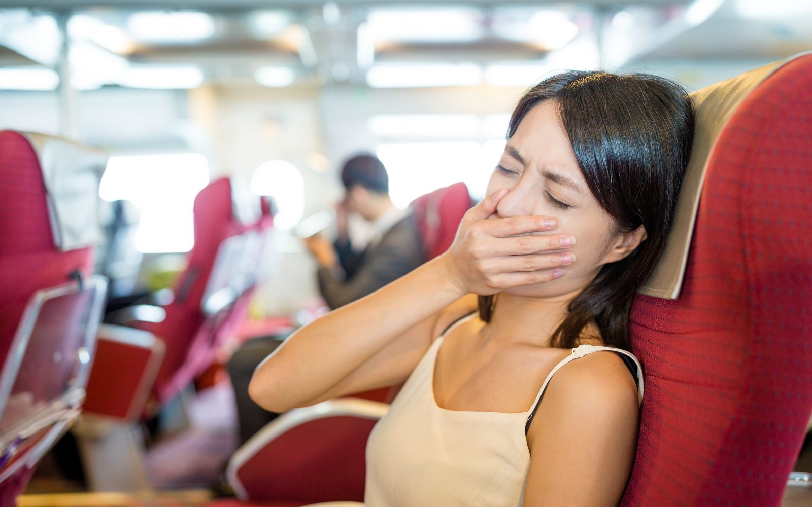 Ženska z morsko boleznijo na ladji, drži se za usta in kaže znake slabosti in morske bolezni.