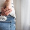 Moški daje kondom v žep kavbojk. Preprečevanje spolno prenosljivih bolezni in aidsa. Preudaren moški s kondomom.