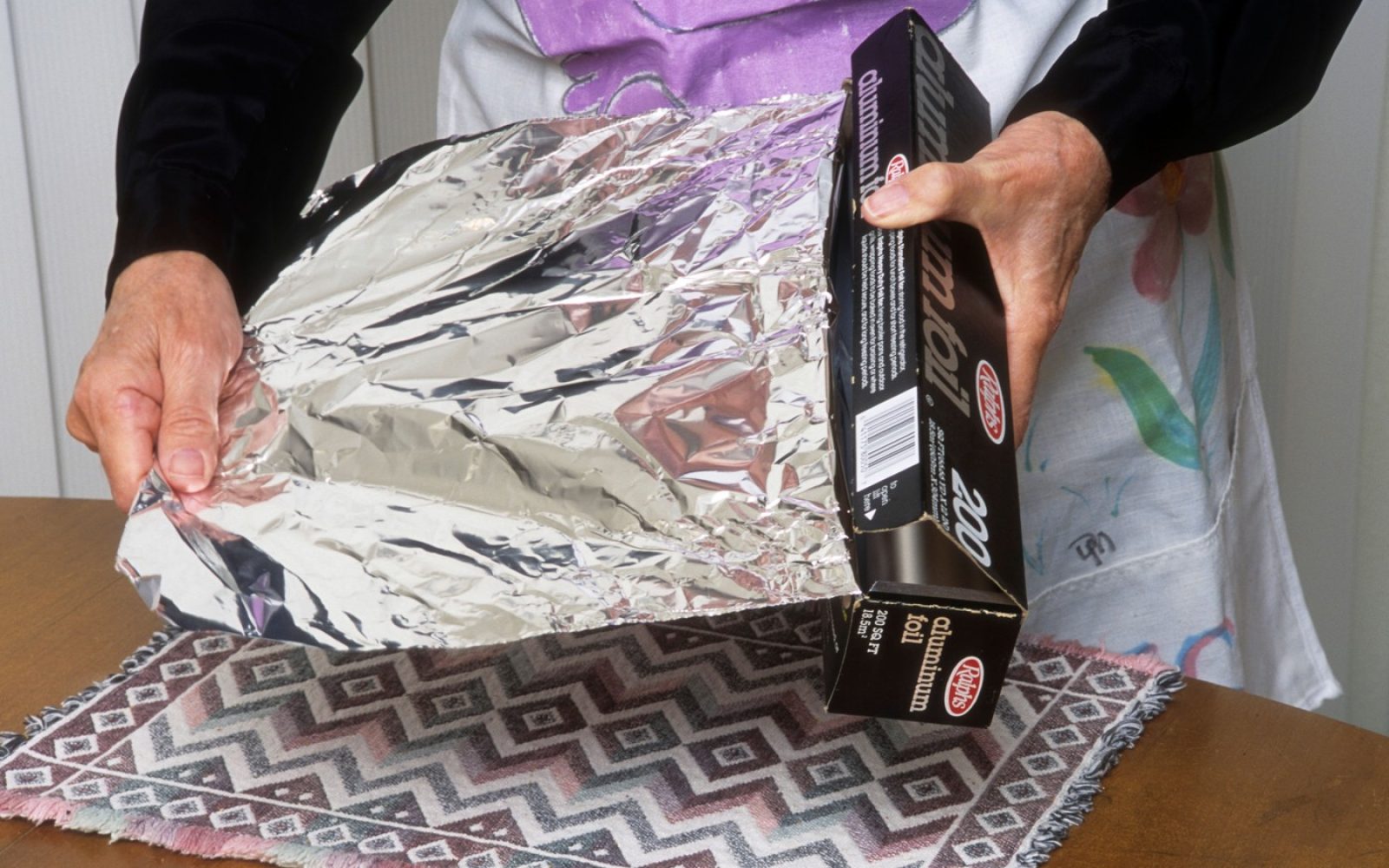 Oseba drži aluminijasto folijo – razlaga, kaj se zgodi, če jo pogoltnemo, in kdaj je nujno poiskati zdravniško pomoč