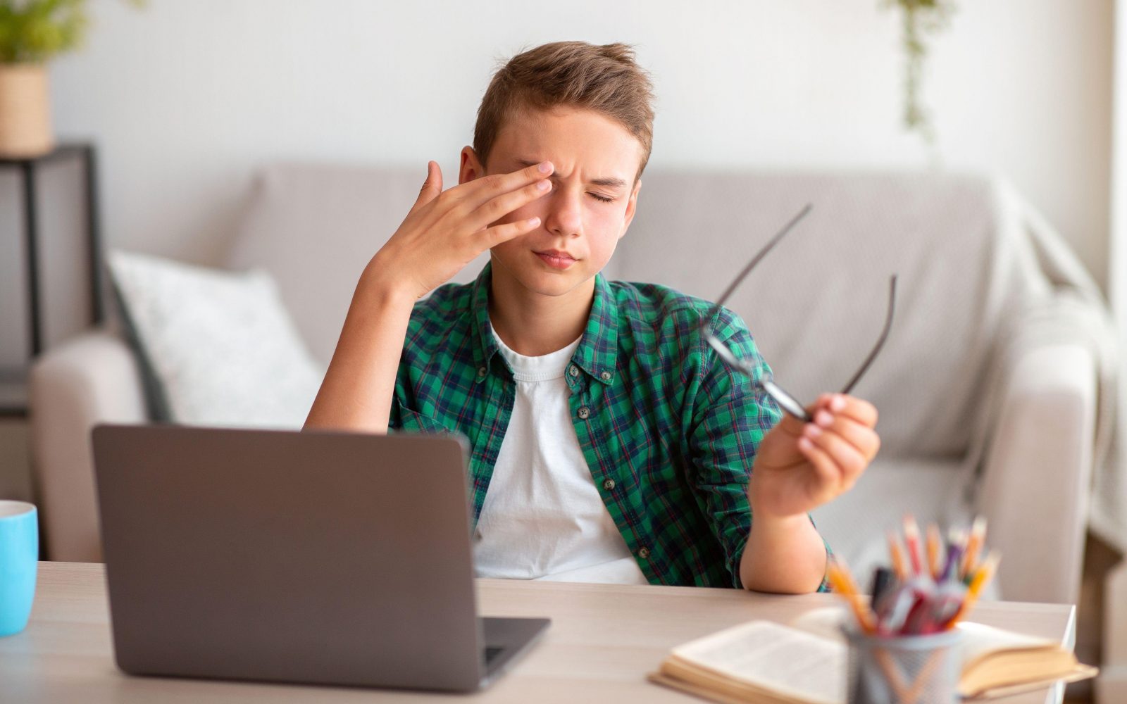 Deček si med učenjem zaradi utrujenosti mane in drgne oči, kar ima lahko trajne škodljive posledice.