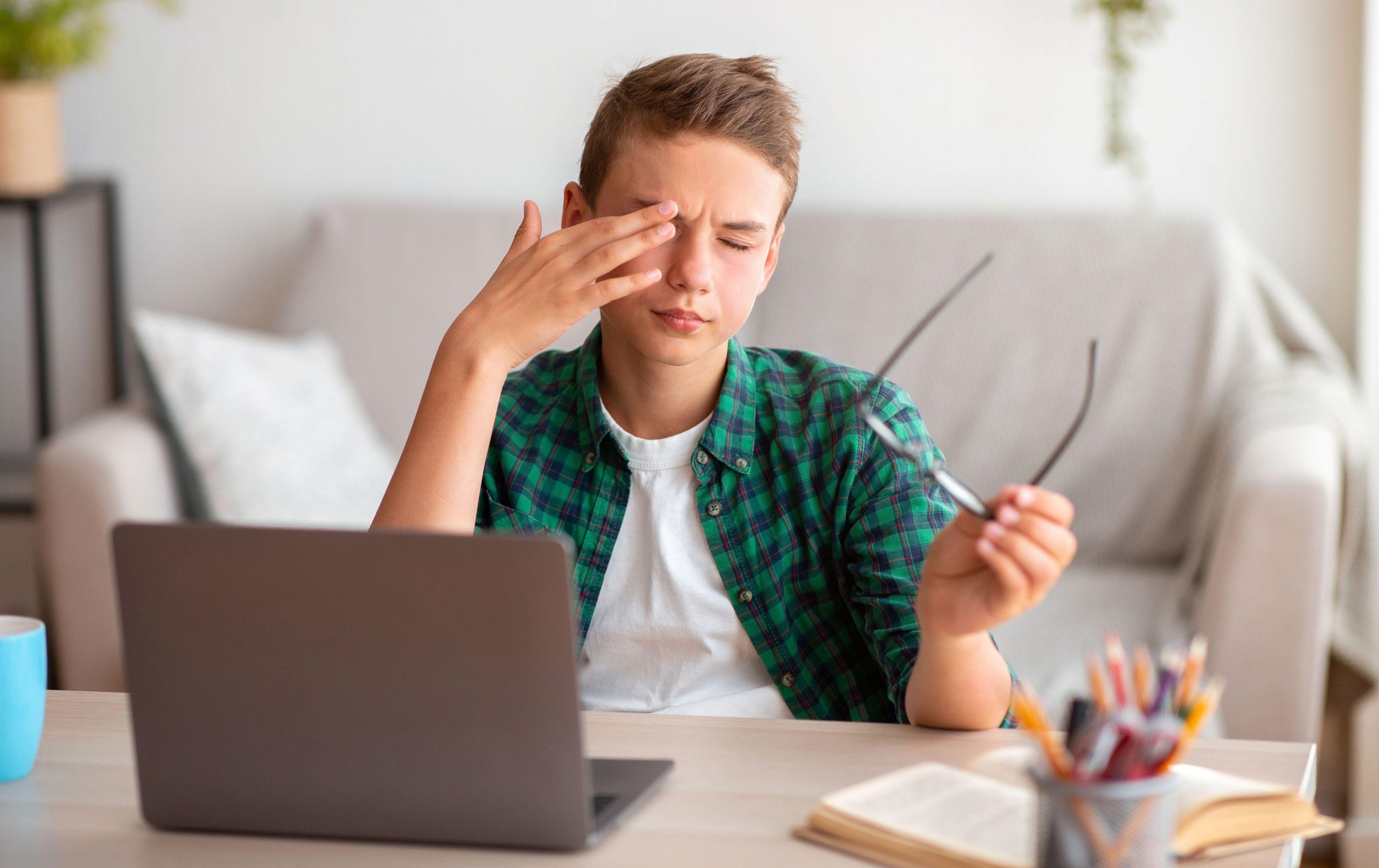 Deček si med učenjem zaradi utrujenosti mane in drgne oči, kar ima lahko trajne škodljive posledice.
