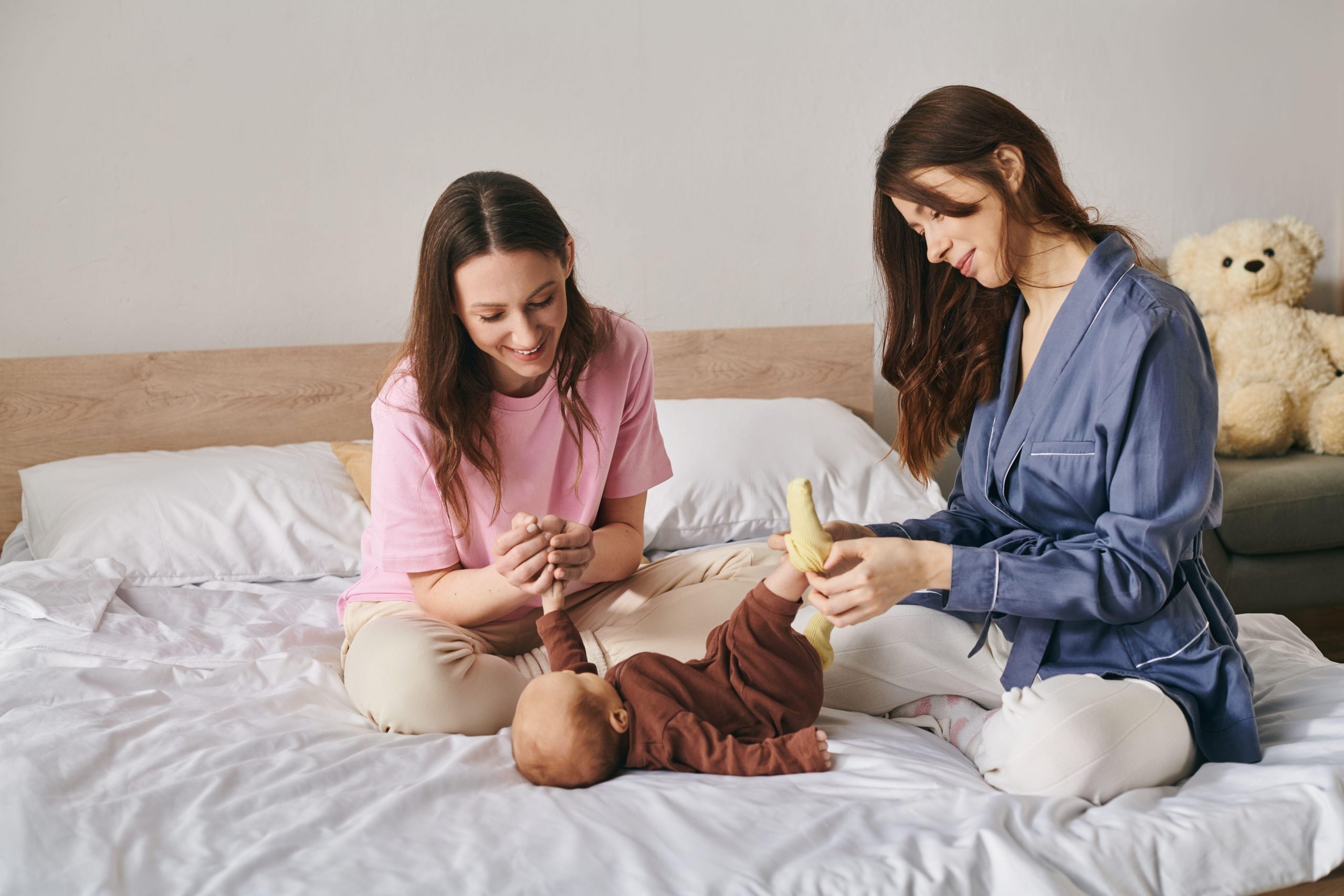 Dve srečni nasmejani materi se igrata s svojim otrokom - nove možnosti materinstva z humanoidnimi nosečniškimi roboti