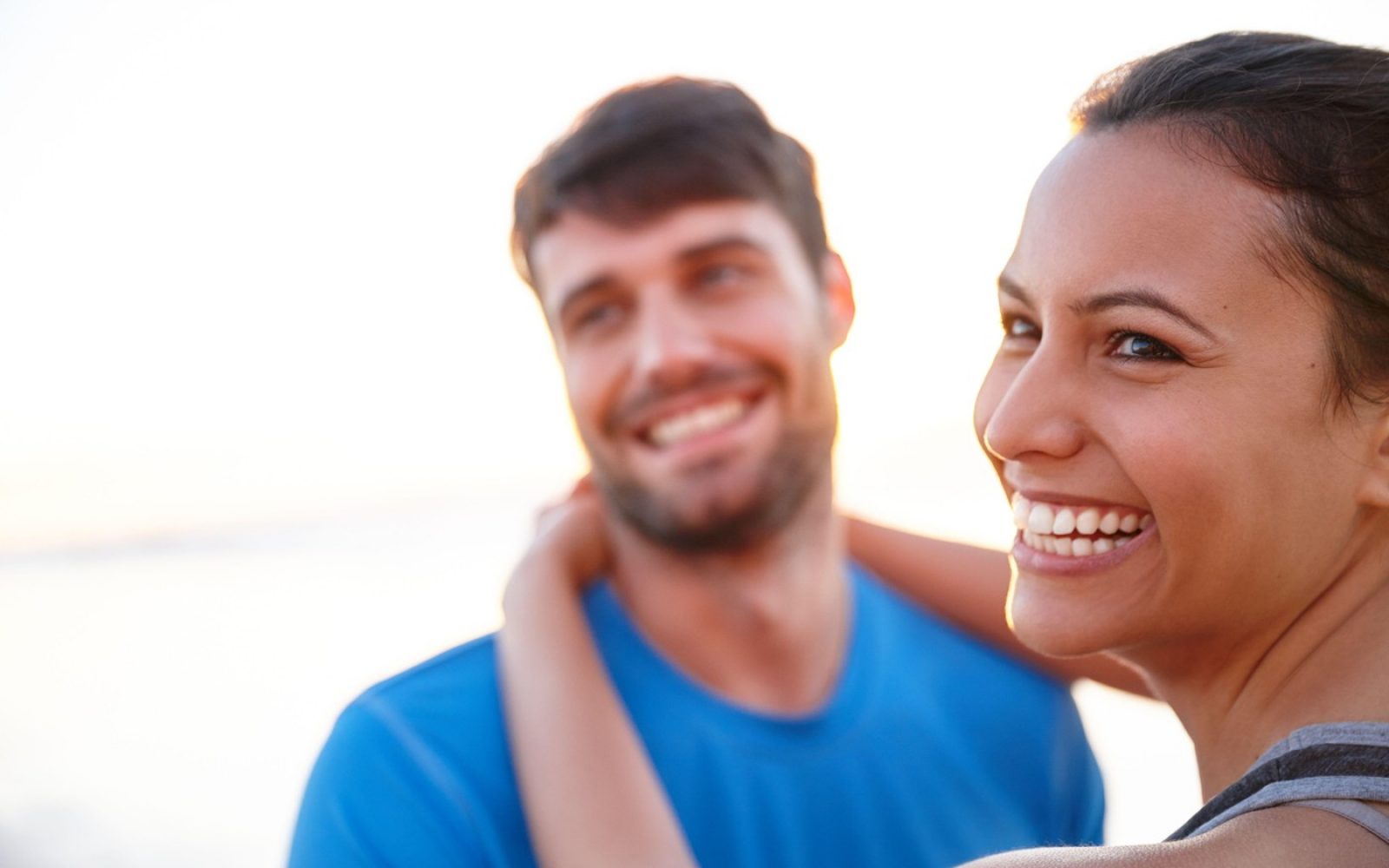 Srečen mlad par na plaži ob sončnem zahodu – poletje, ljubezen in ozaveščanje o zaščiti pred HPV
