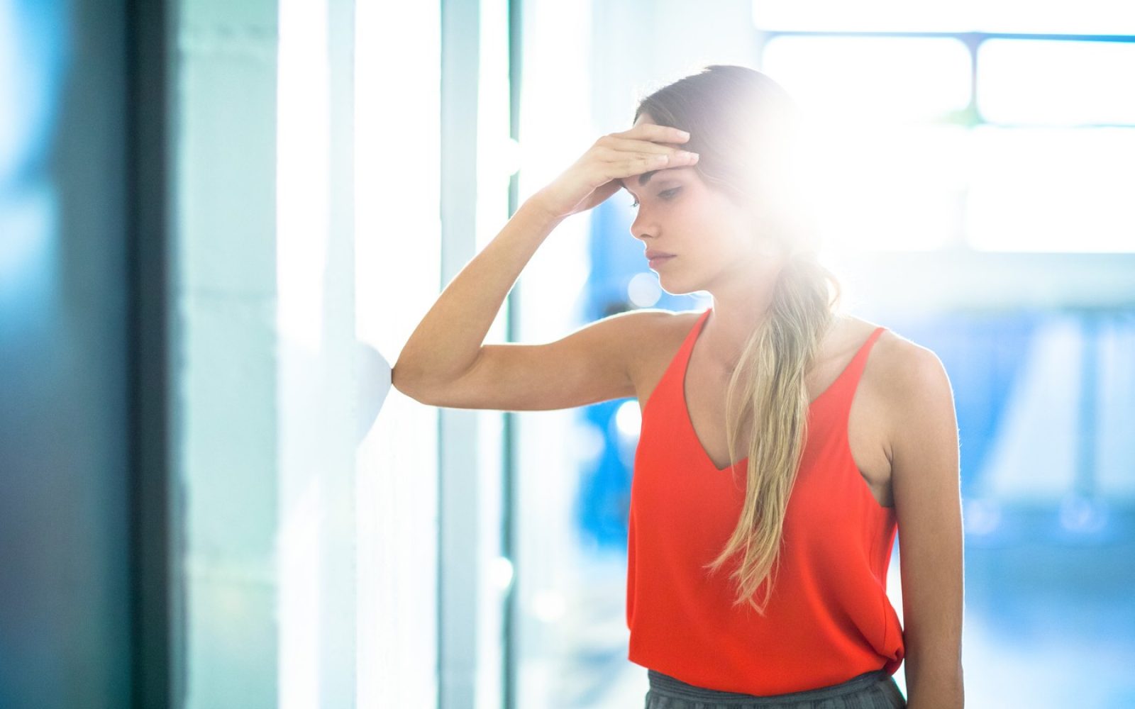 Ženska, ki se drži za glavo zaradi utrujenosti in izčrpanosti po vročem dnevu.