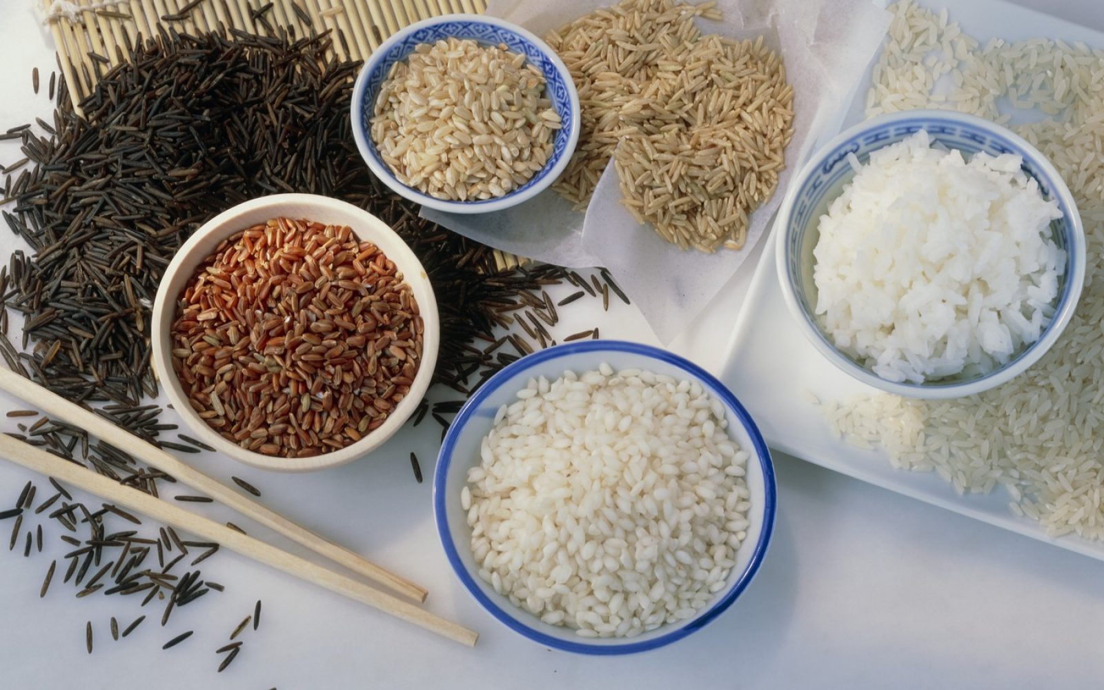 Različne vrste riža (Oryza sativa). V smeri urinega kazalca, od spodaj: arborio, camargue rdeči riž, divji riž, basmati, rjavi dolgozrnati, beli dolgozrnati in kuhan beli dolgozrnati riž. Riž je osnovno živilo za približno polovico svetovnega prebivalstva. Bogat je z ogljikovimi hidrati in vitamini skupine B.  