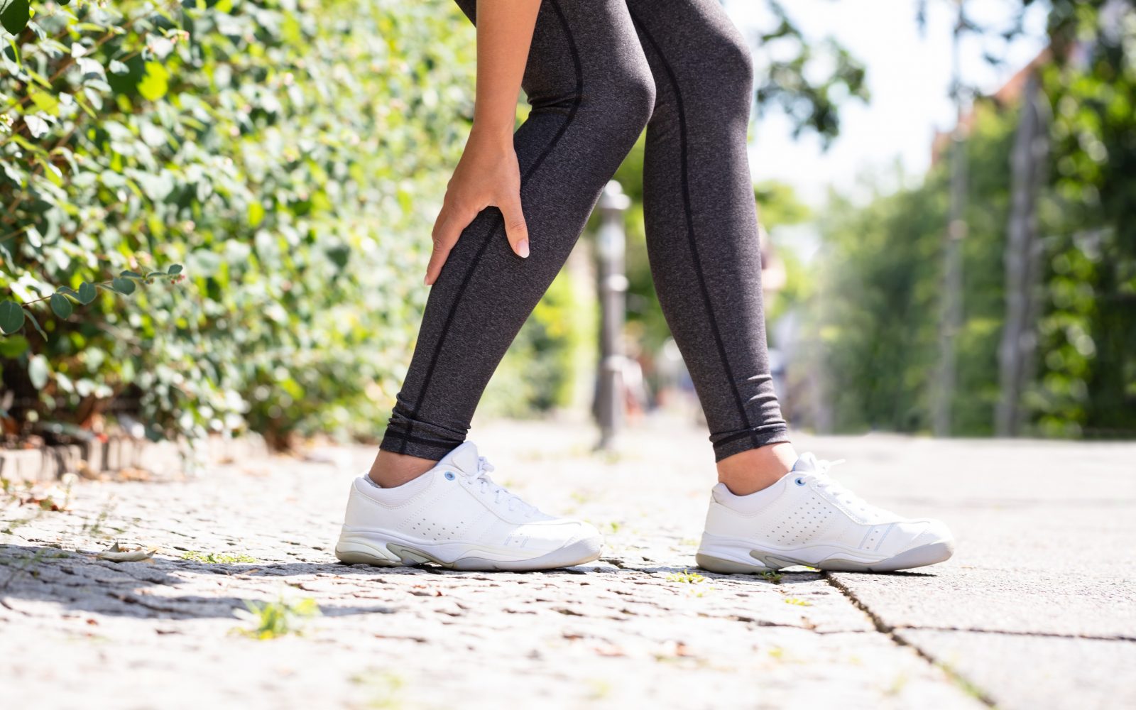 Ženska se drži za bolečo mišico, ima musklfiber, bolčino po vadbi