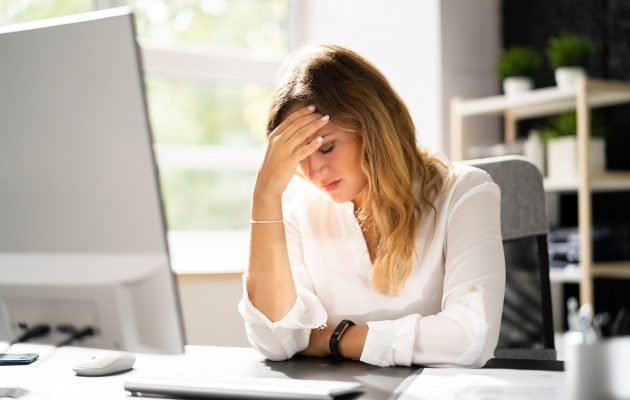 Utrujena ženska se drži za glavo