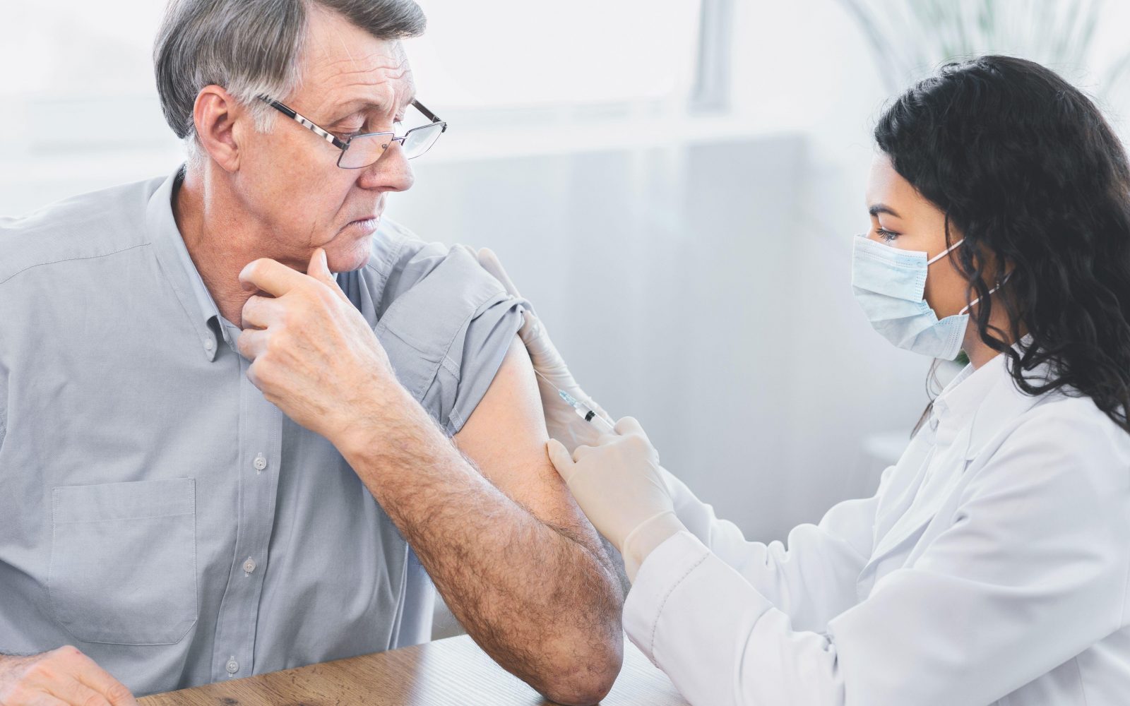 Zdravstvena delavka cepi starejšega moškega. Starejše ljudi nalezljive bolezni bolj ogrožajo, zato je dobro, da se cepijo