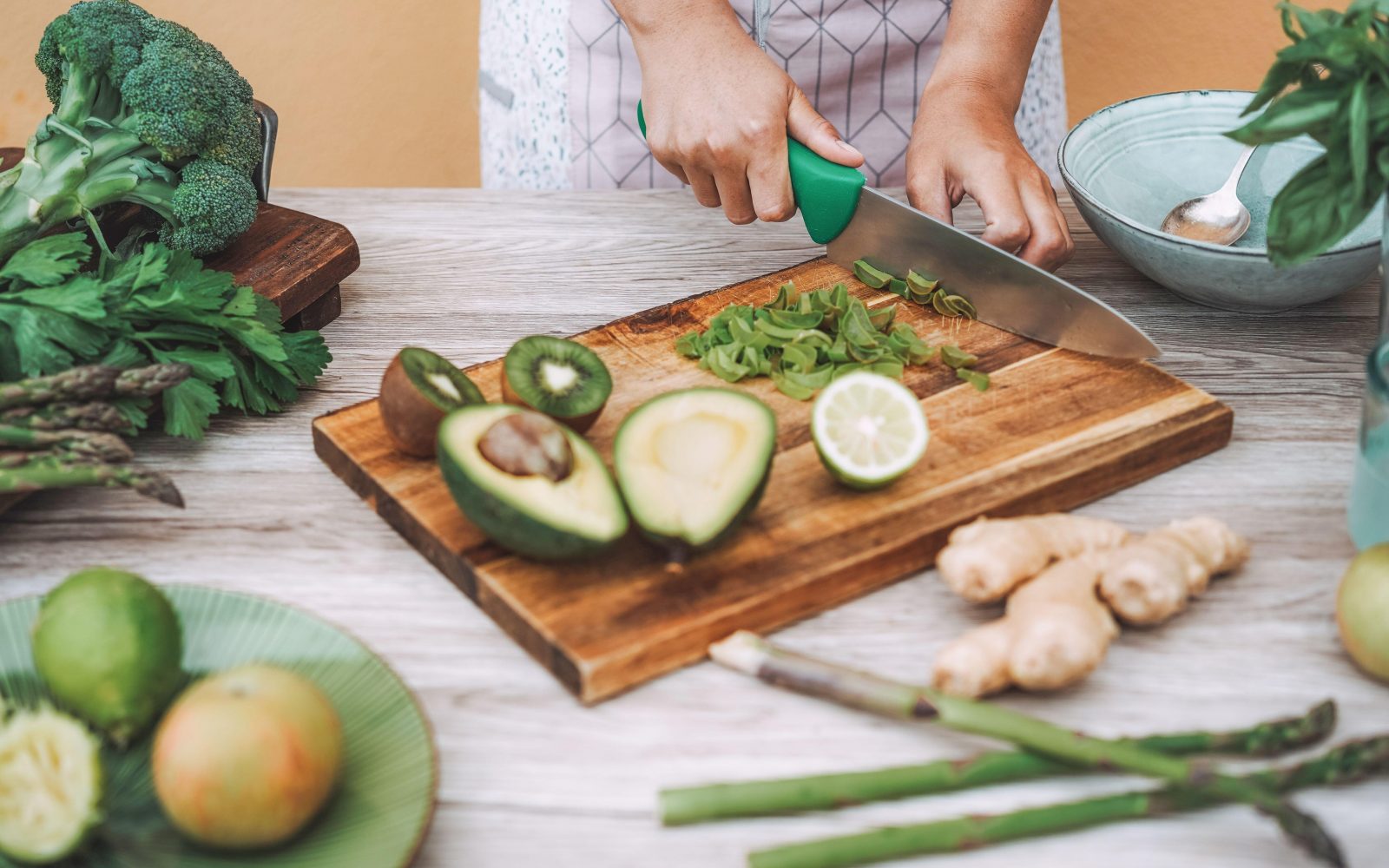 Mlada ženska pripravlja zdrav napitek iz kivija, ingverja, avokada, limete in bazilike, s katerim bo zaužila vitamine in minerale za odpornost.