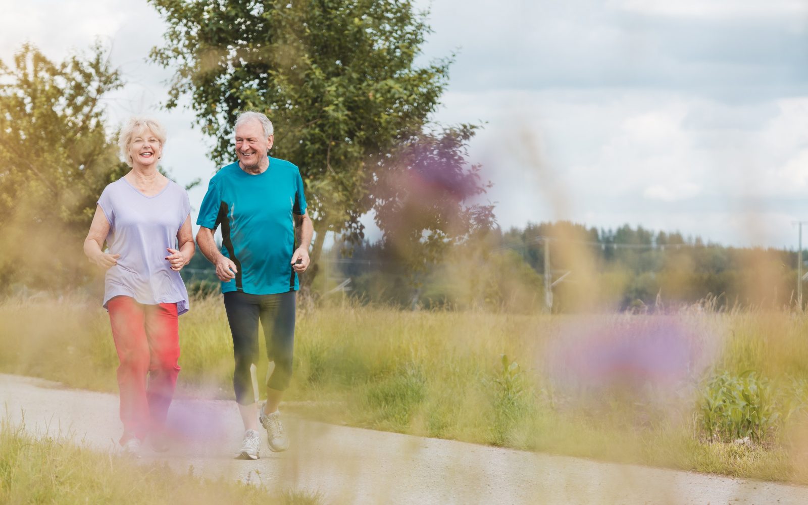 Fit in aktiven starejši par, ki poleti teče na prostem.