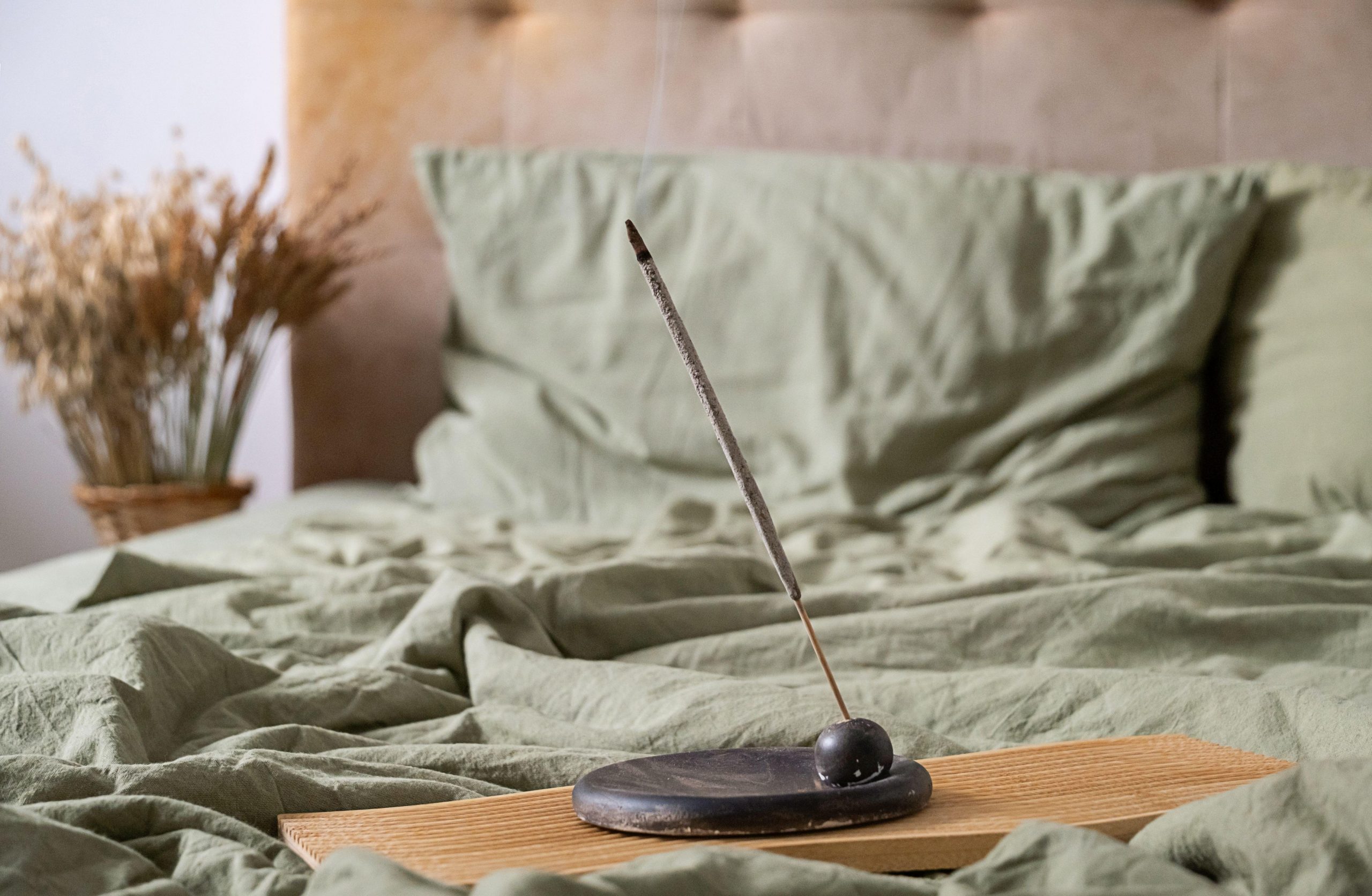 Dišeča palčka v spalnici na postelji - aromaterapija kot tehnika za obvladovanje anksioznosti.