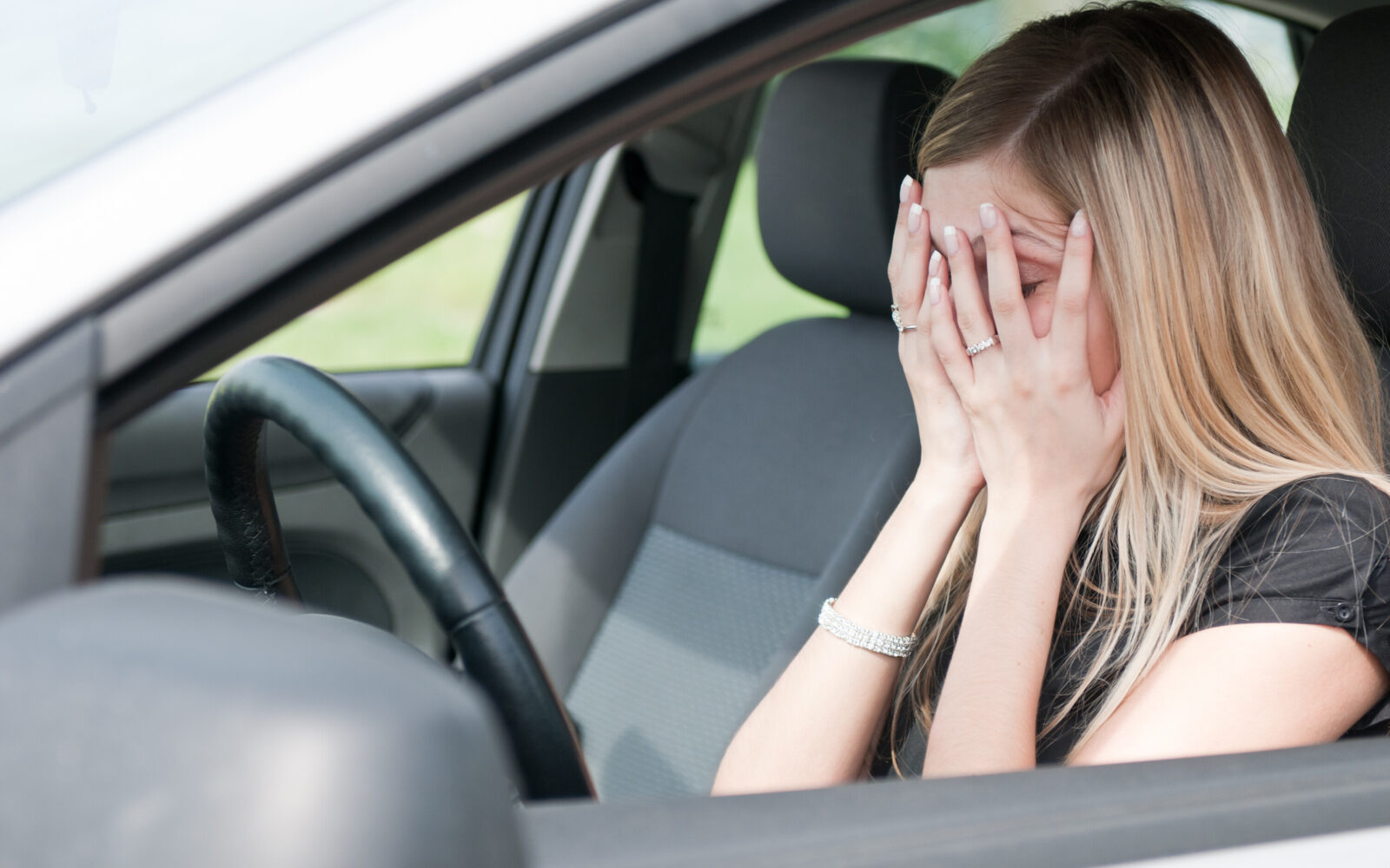 Ženska v avtu si prekriva roke z dlanmi