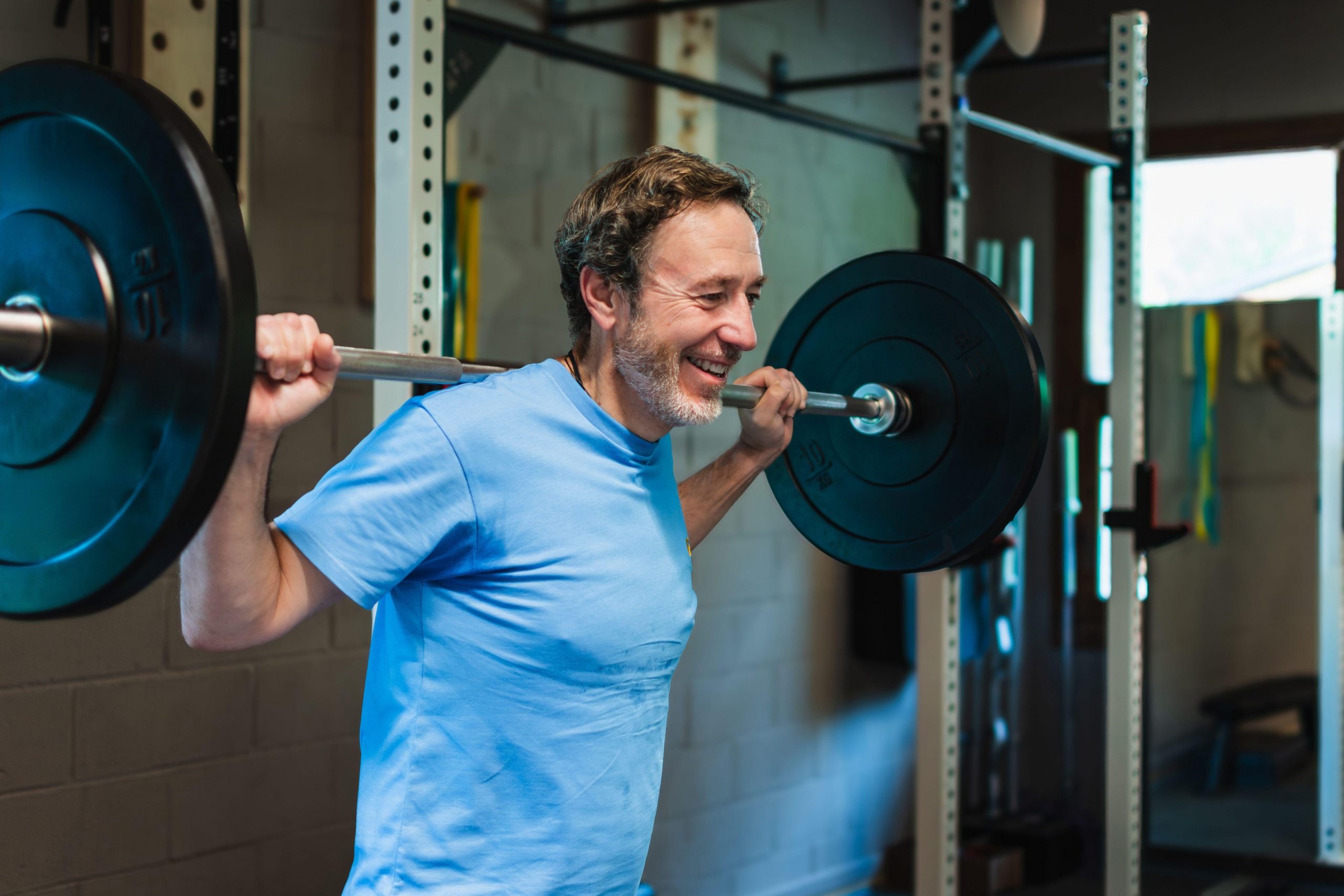 Starejši odrasel moški v fitnesu dviguje utež - odličen način za krepitev mišic, ohranjanje kondicije, krepitev zdravja srca in ravnotežja