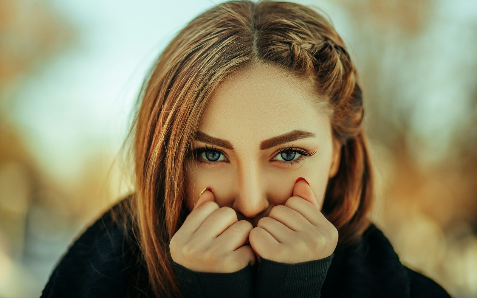 lepa ženska, v jesensko zimskem času, stiska dlani k obrazu, ker je mraz