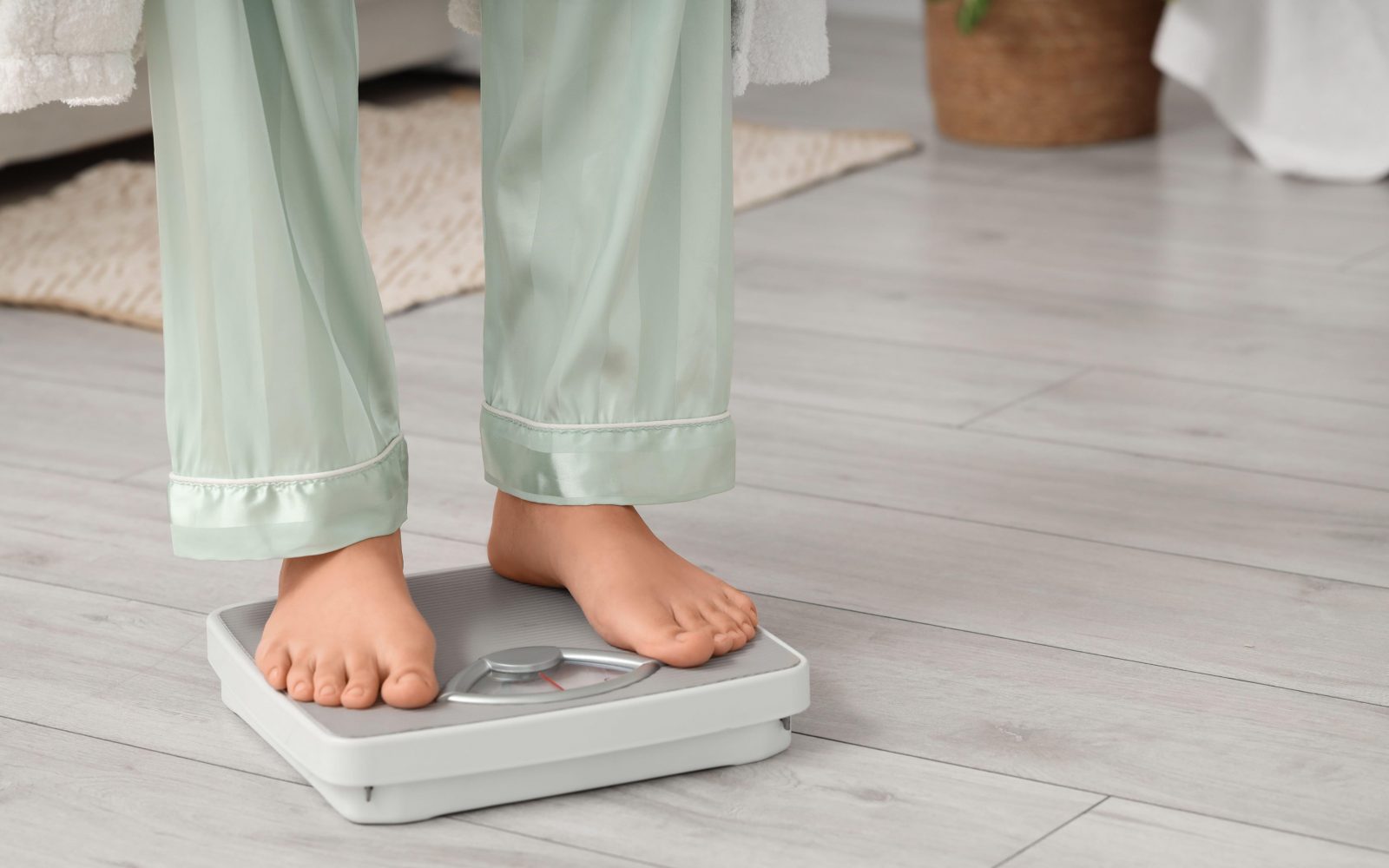 nekdo stoji na tehtnici in se tehta, simbolika uravnavanje telesne mase