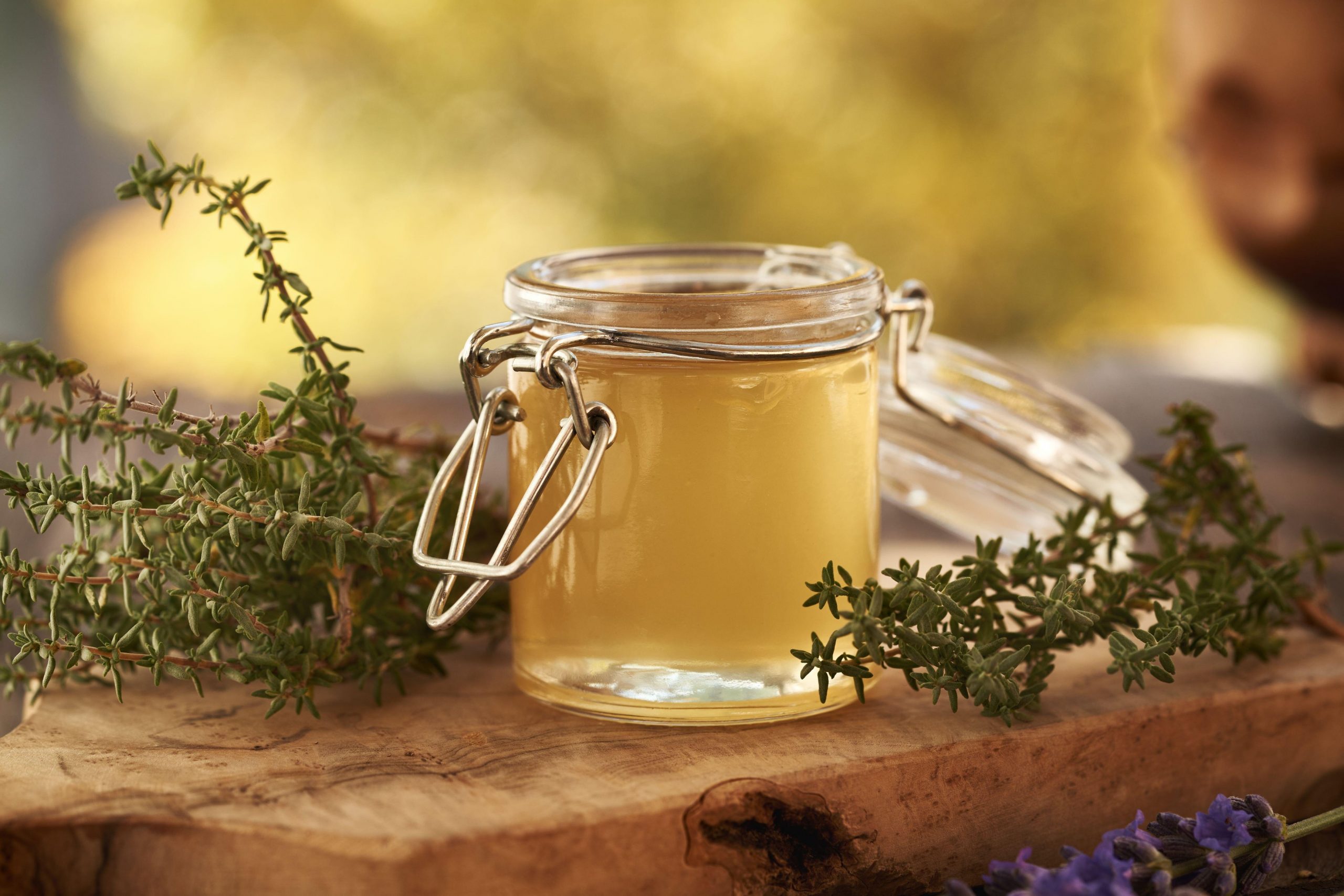 Kozarec timijanovega sirupa in timijanove vejice na leseni mizi.