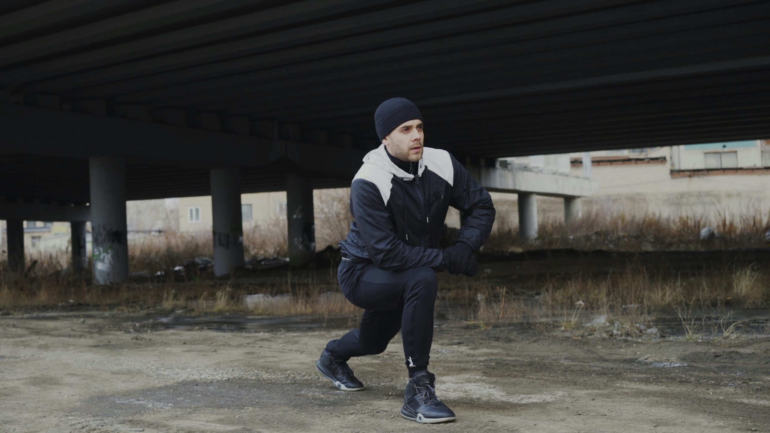 Moški se pred začetkom športne aktivnosti ogreva. Zunaj je zima in mraz