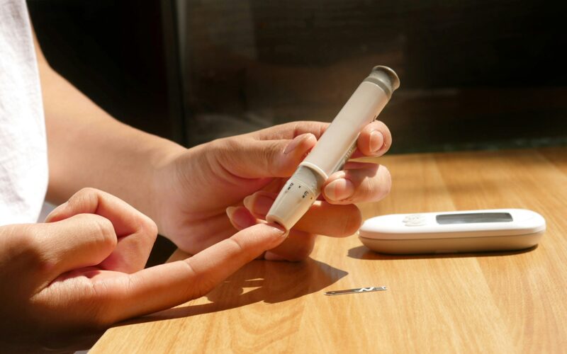 Oseba si meri raven glukoze v krvi iz prsta