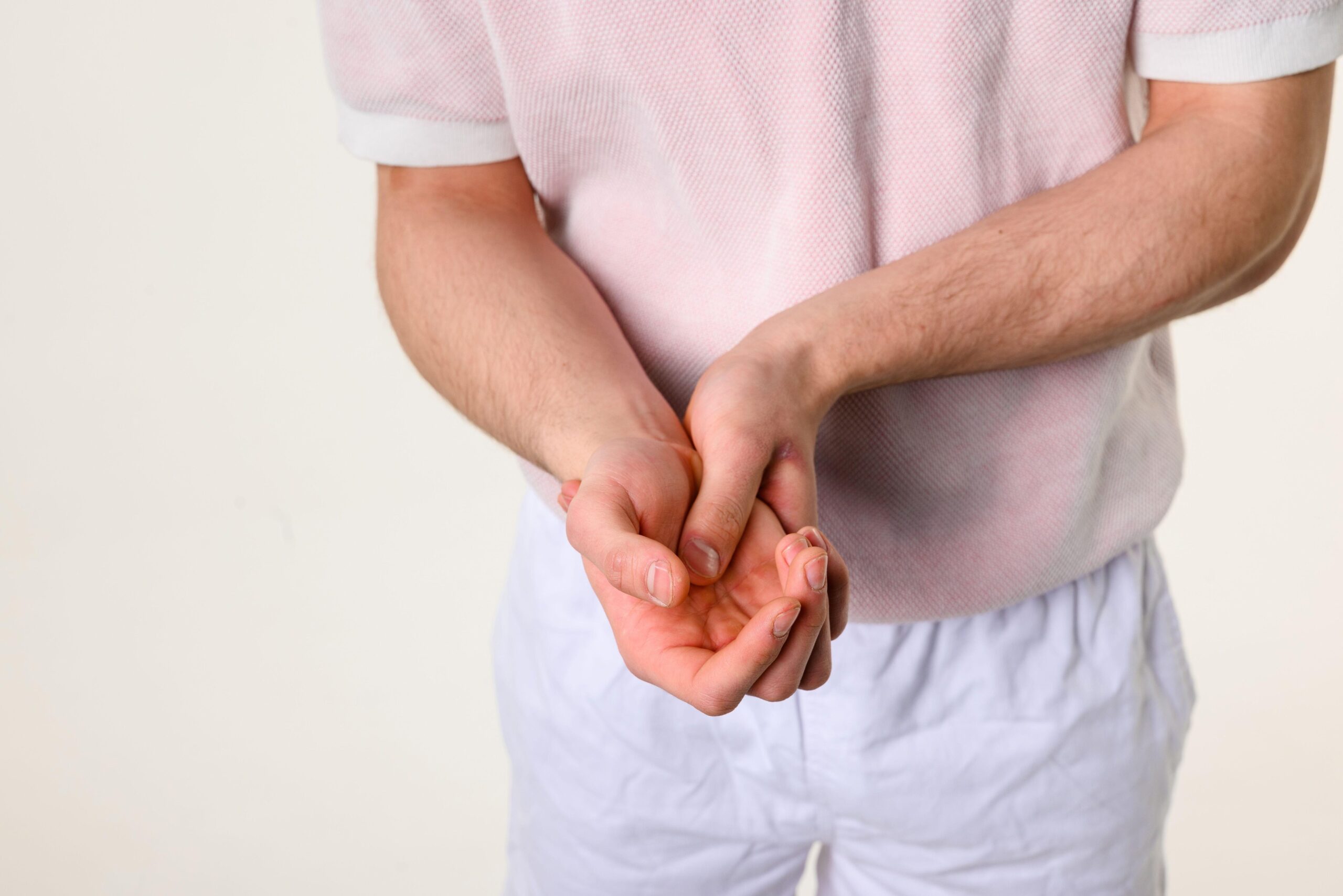 Moški se drži za roko, roka je paralizirana