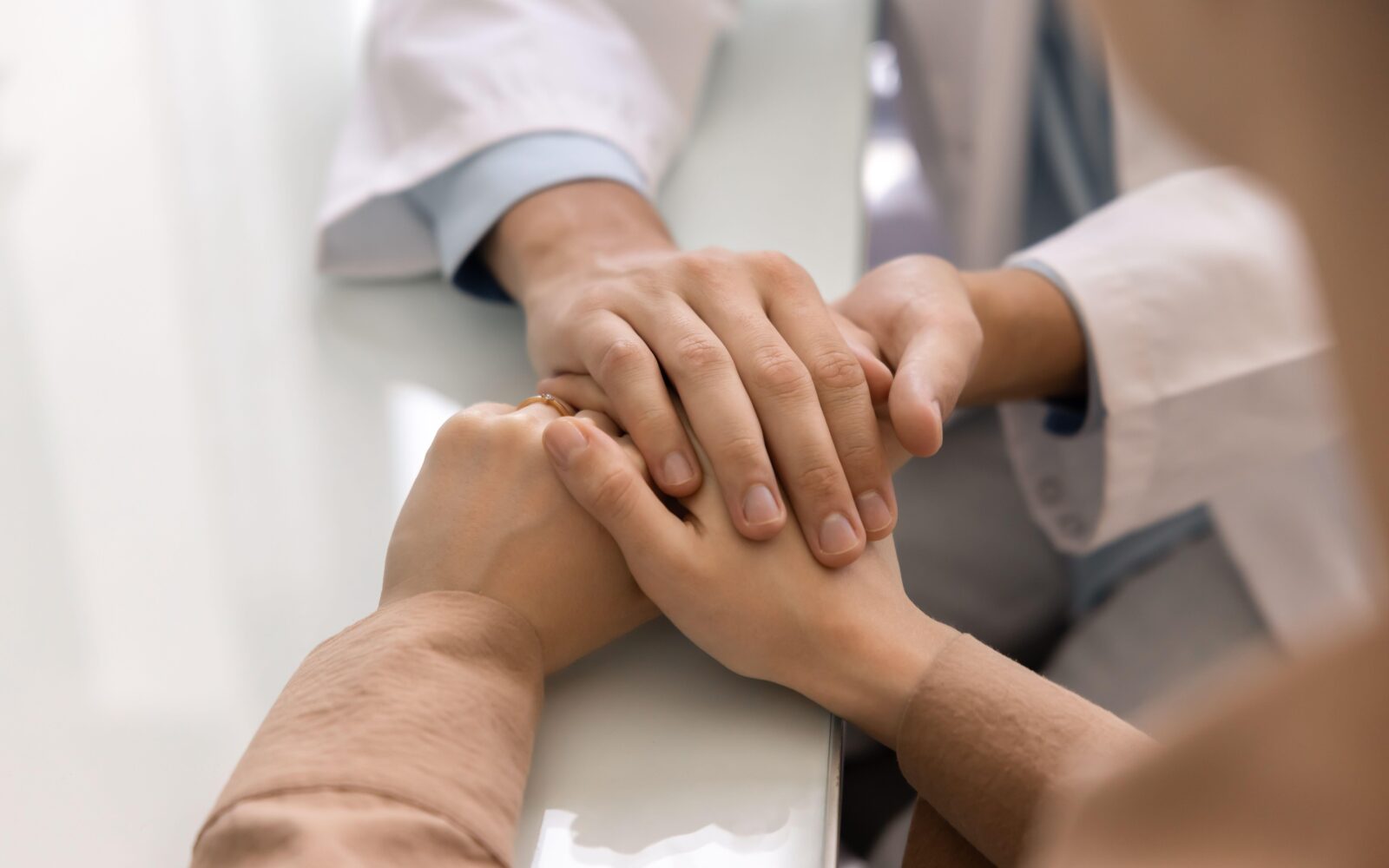 Ginekolog drži za roko pacientku, prikaz zaupanja, strokovne podpore in svetovanja.