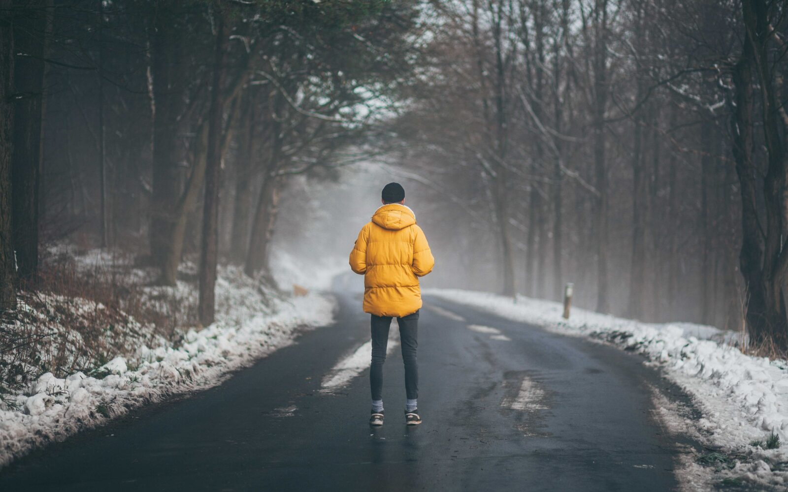 Ženska v rumeni budni stoji sredi ceste. Je zima in mraz