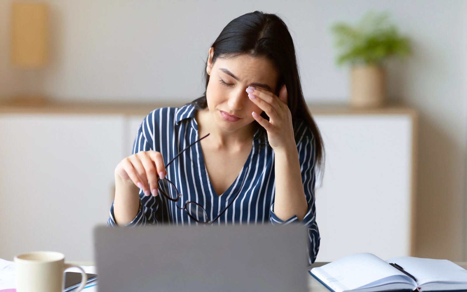 Mlajša ženska sedi za računalnikom, drži se za oko