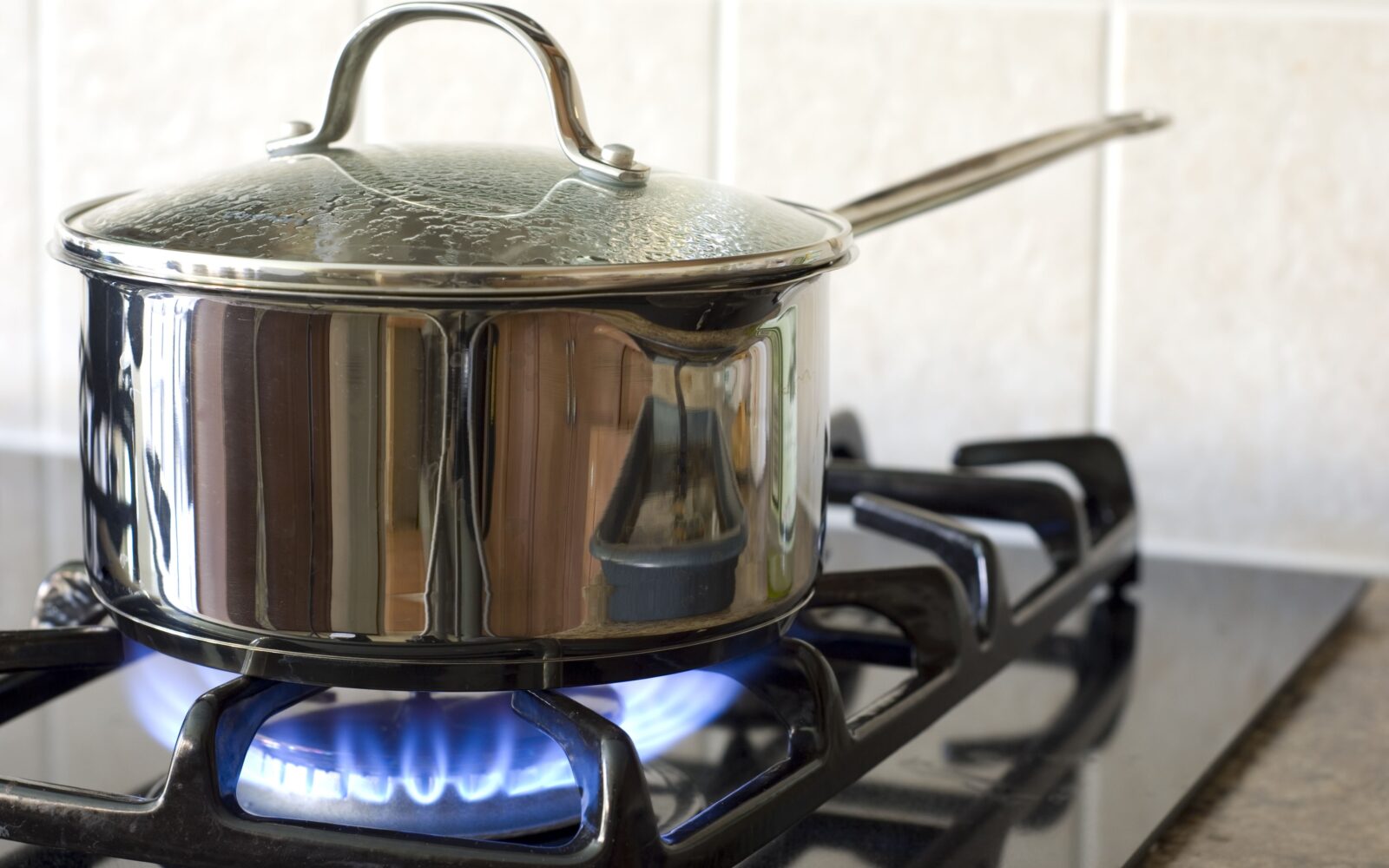 Na plinskem štedilniku je lonec, nekaj se kuha z močnim ognjem