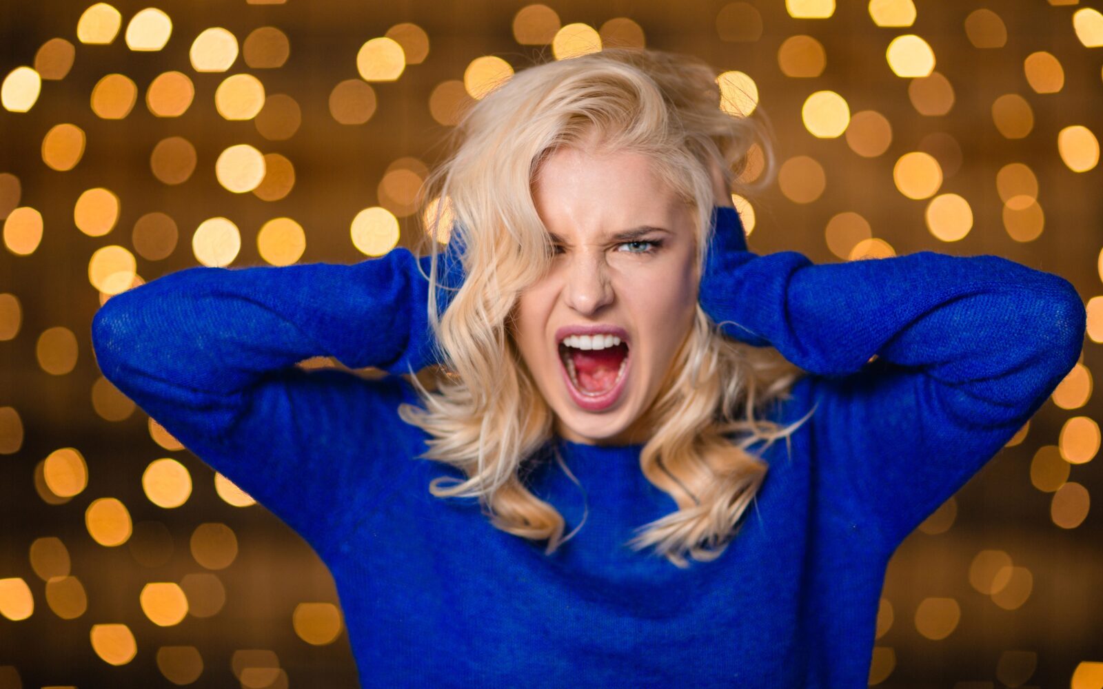 Lepa svetlolasa ženska si pokriva ušesa zaradi glasnih pokov pirotehnike, petard in ognjemeta