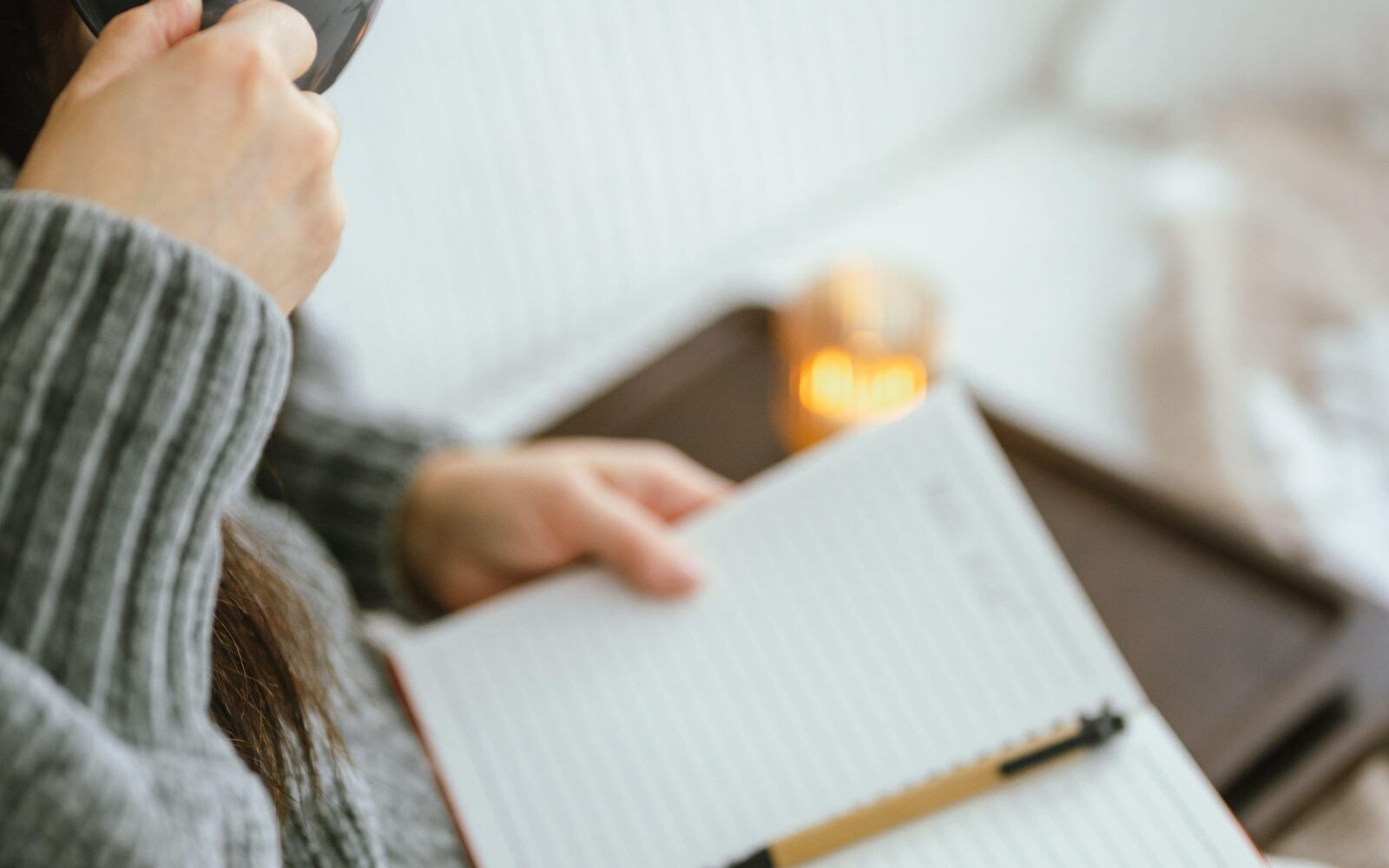 Mlada ženska pije kavo in piše svoj dnevnik hvaležnosti