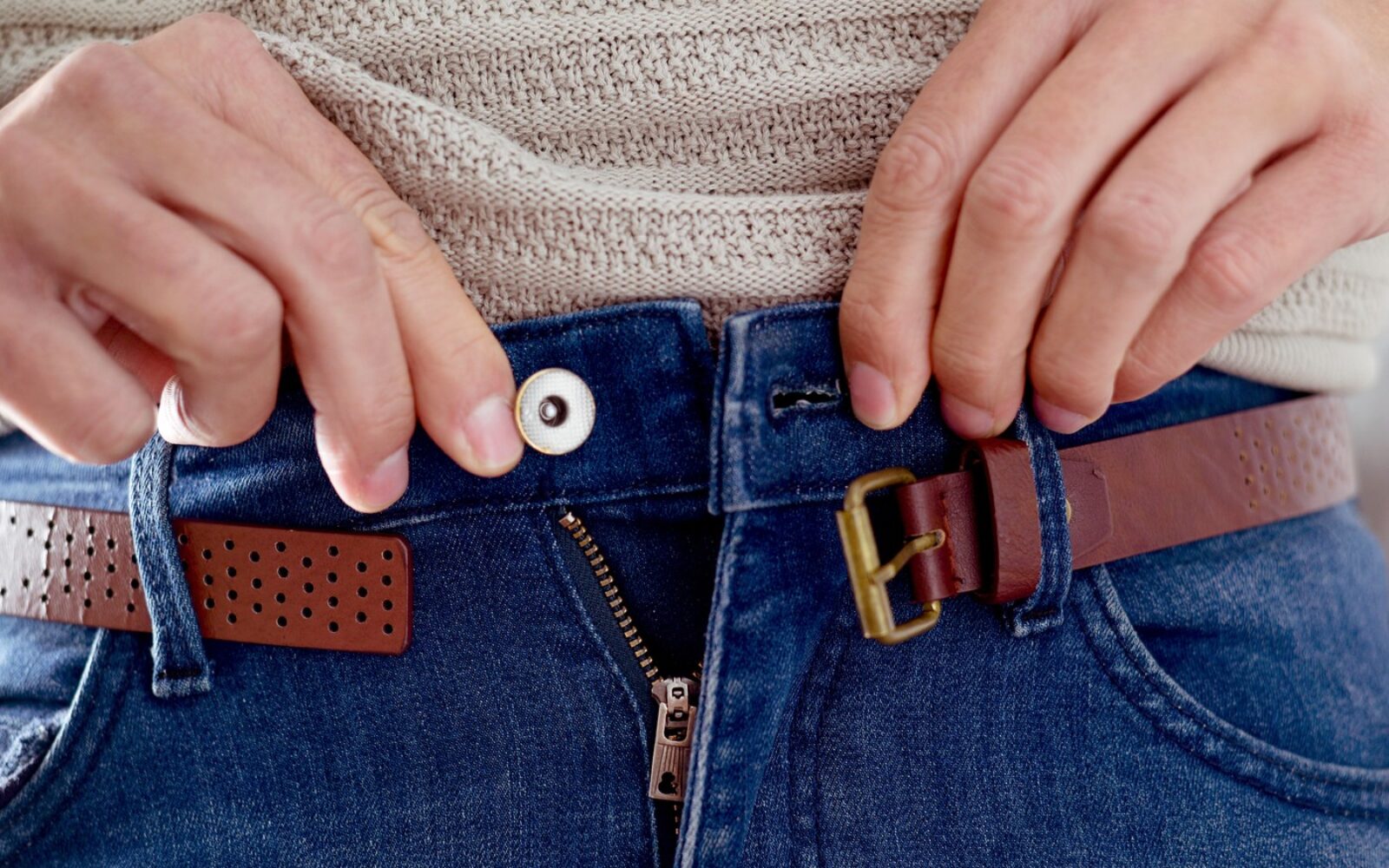 Hujšanje: ženska zapenja tesne kavbojke – simbol frustracije in občutkov krivde po januarski dieti